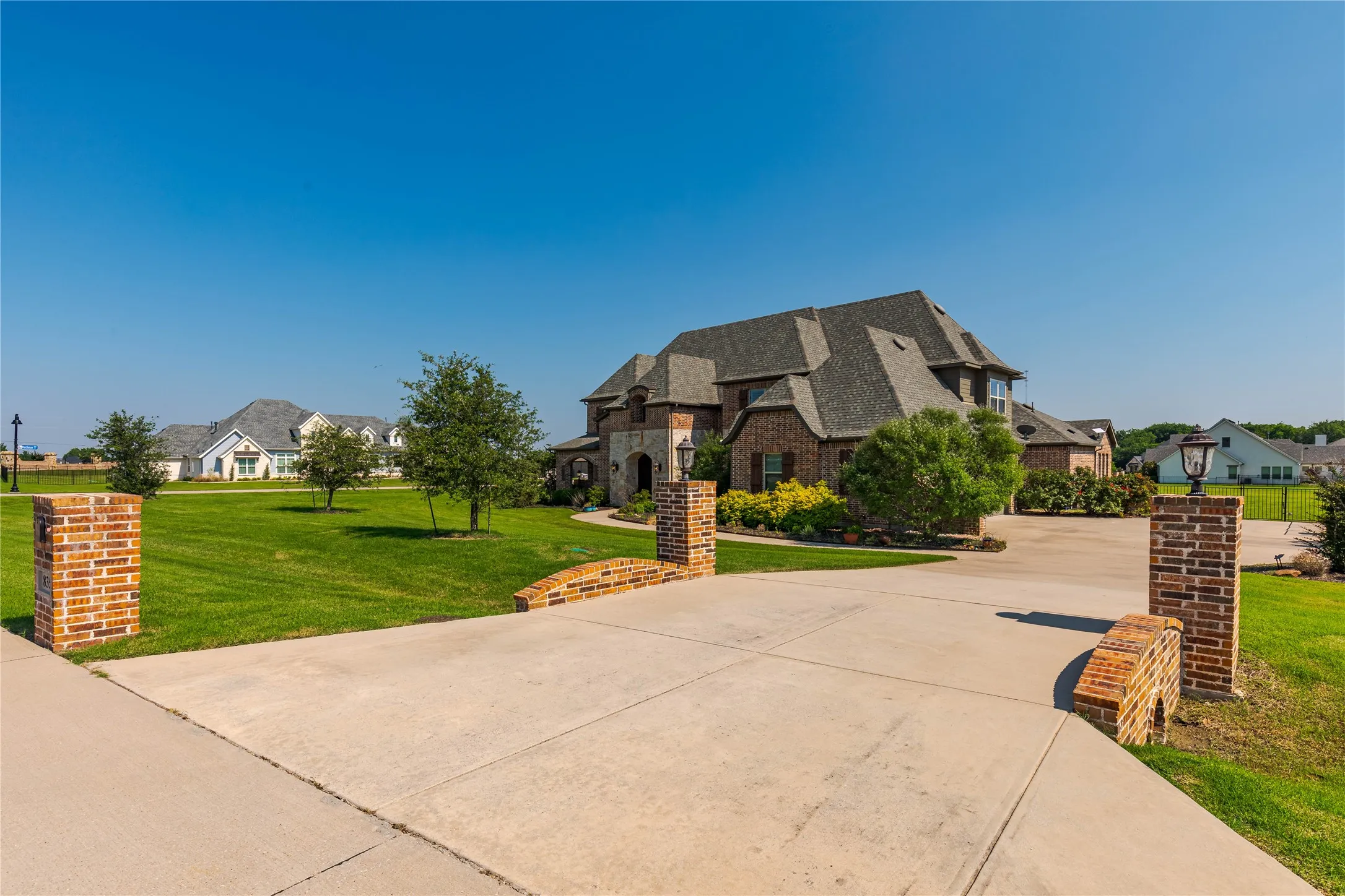 French country inspired facade featuring a front lawn, brick siding, a residential view, and concrete driveway