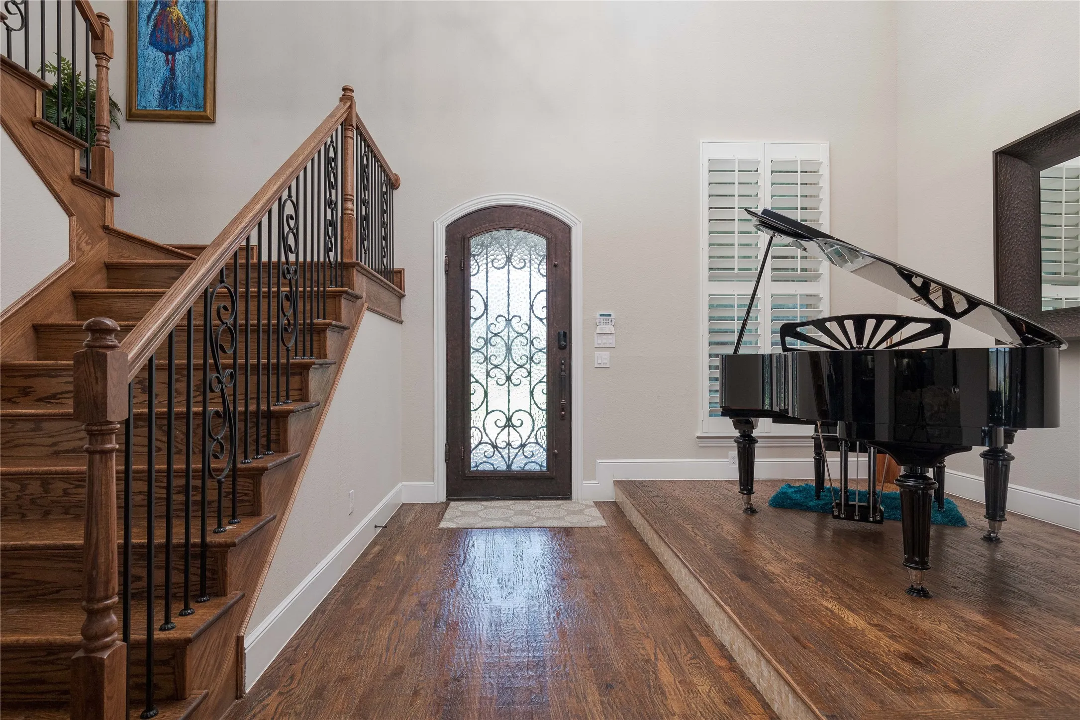 Entrance foyer with baseboards, wood finished floors, a high ceiling, and stairs