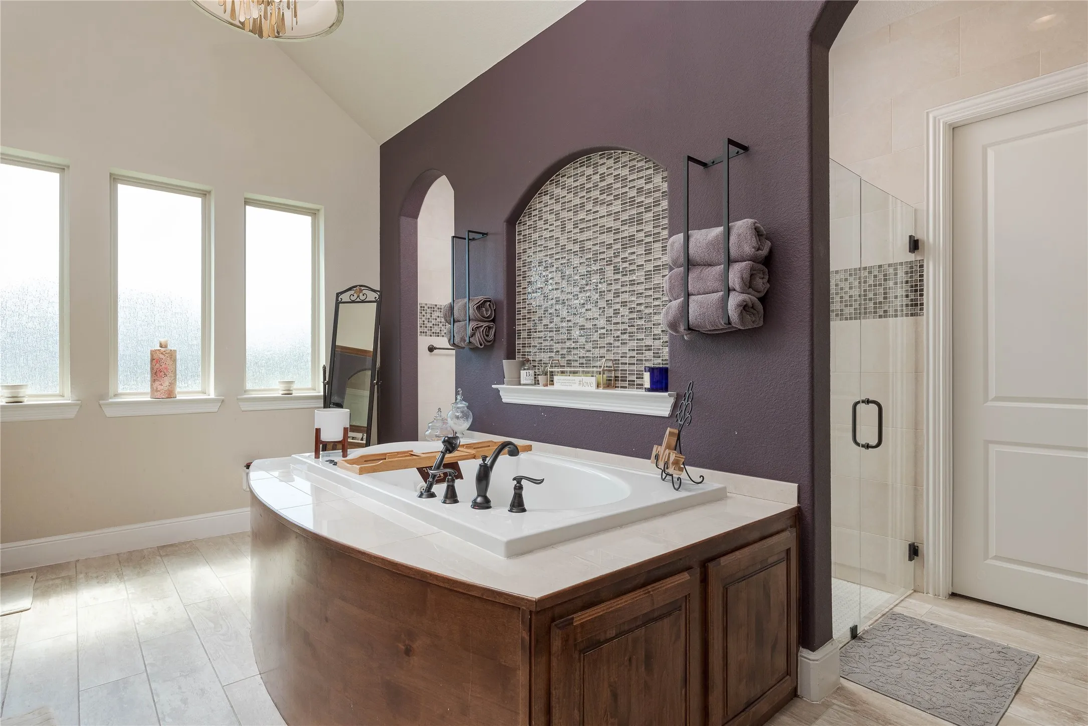 Bathroom with a bath, vaulted ceiling, baseboards, wood finished floors, and a shower stall