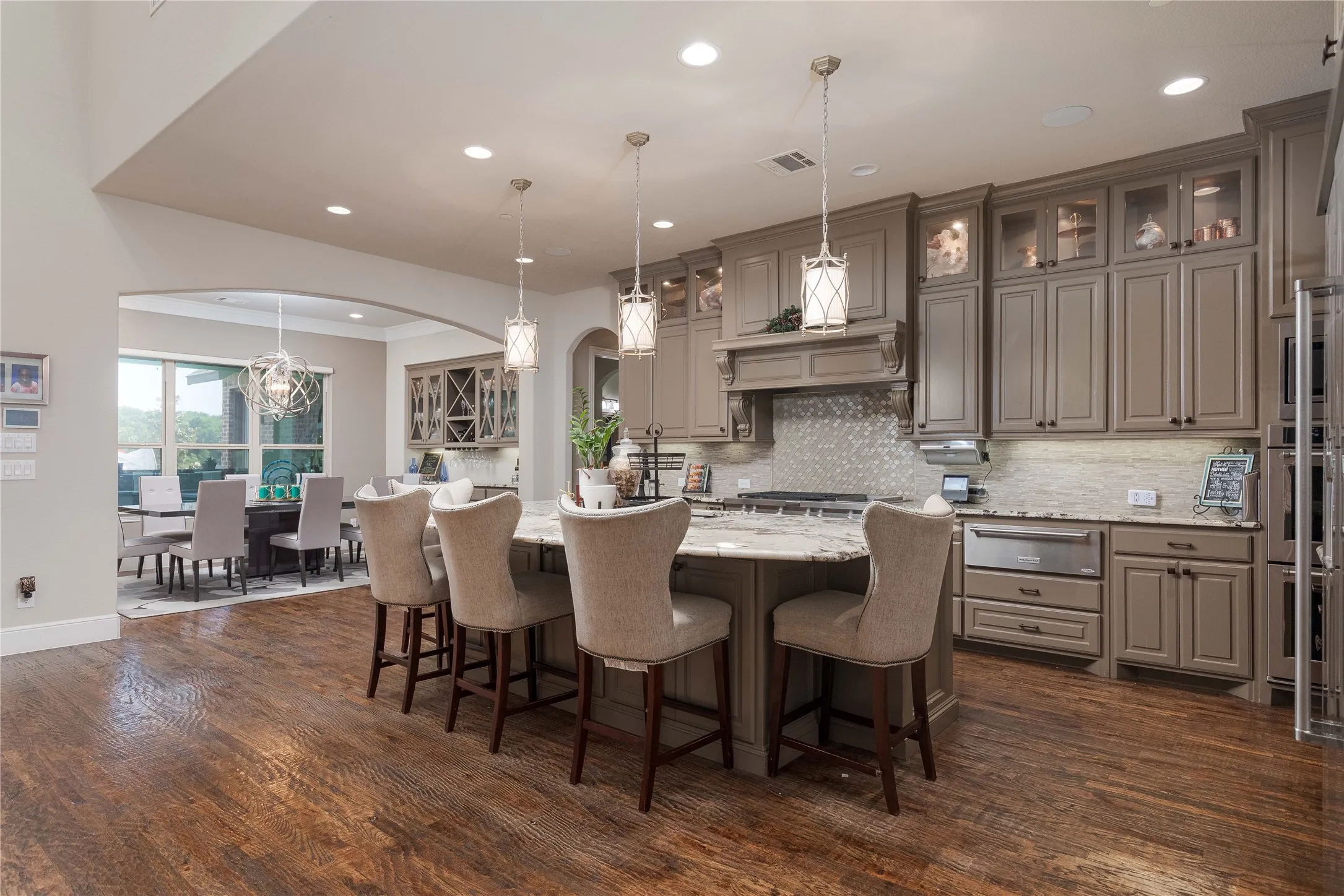 Kitchen with arched walkways, a warming drawer, light stone countertops, decorative backsplash, and gray cabinetry