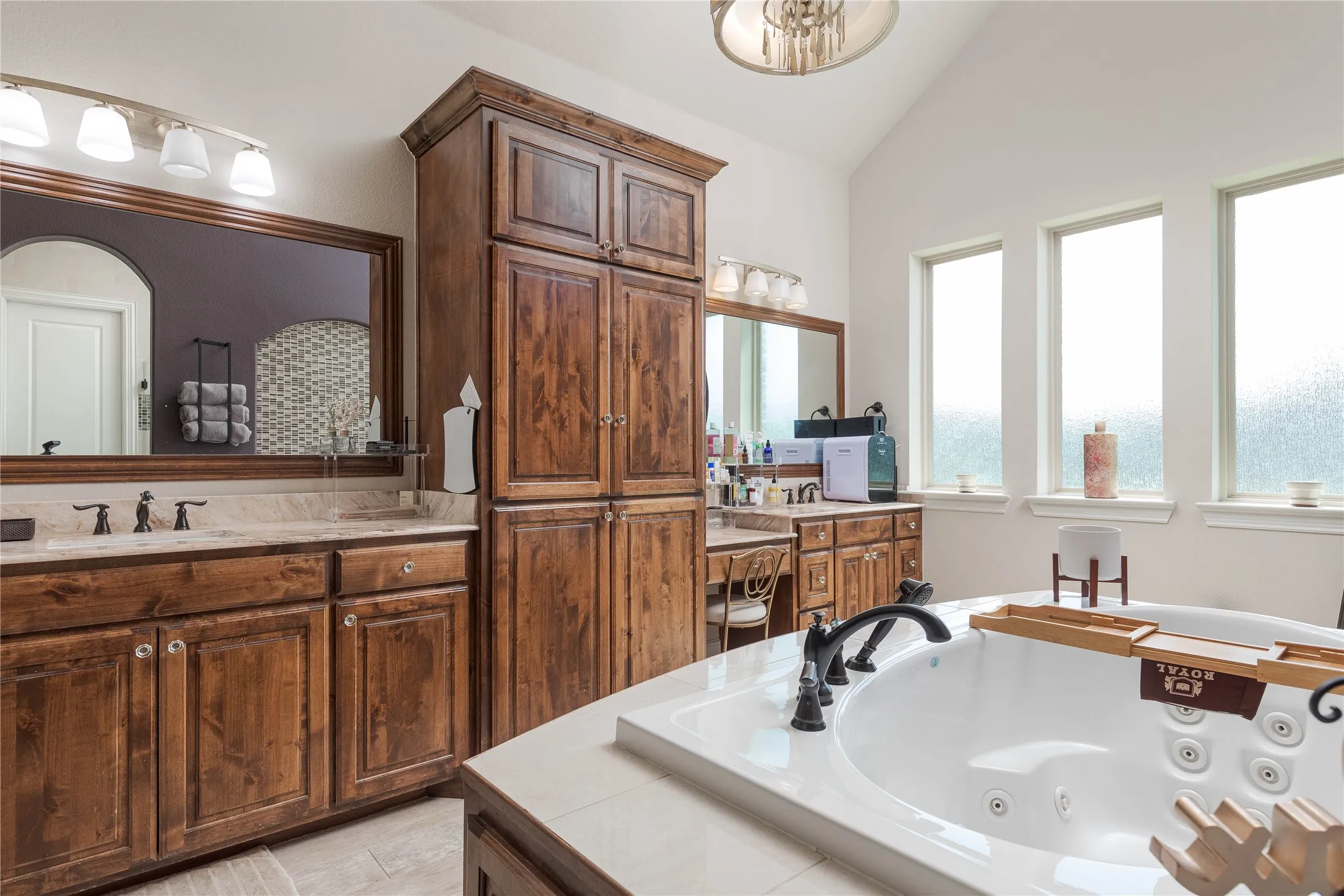 Full bath with lofted ceiling, a healthy amount of sunlight, vanity, and a whirlpool tub