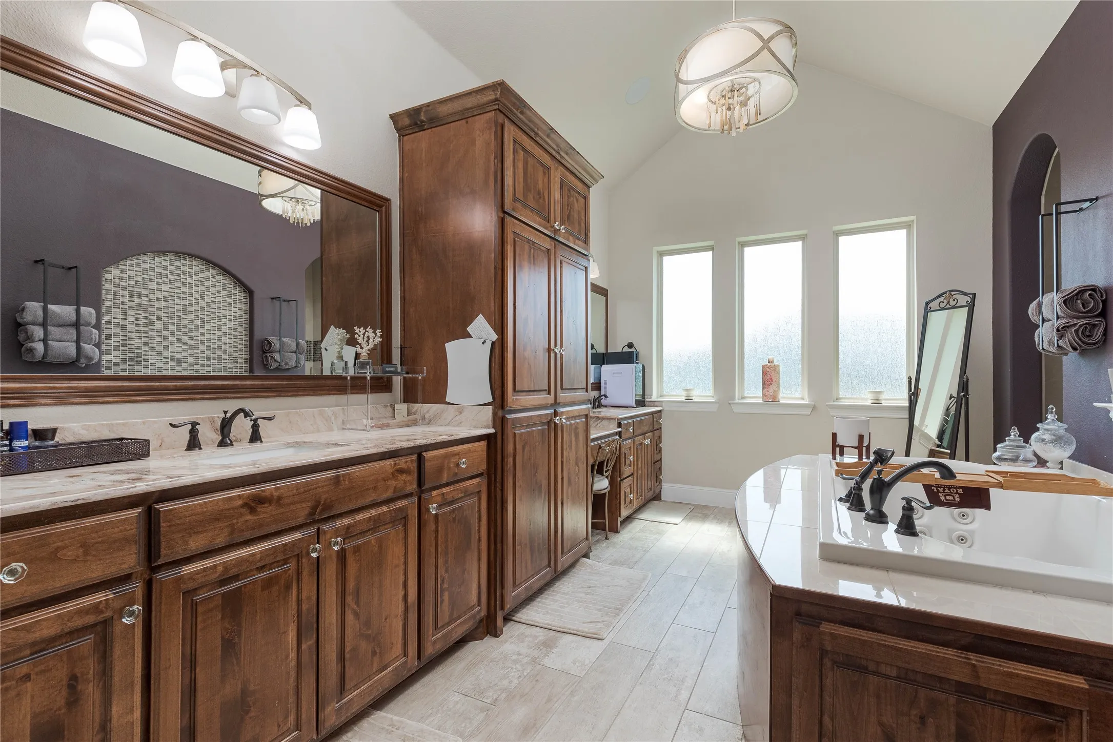 Bathroom featuring a whirlpool tub, vaulted ceiling, vanity, and wood finished floors