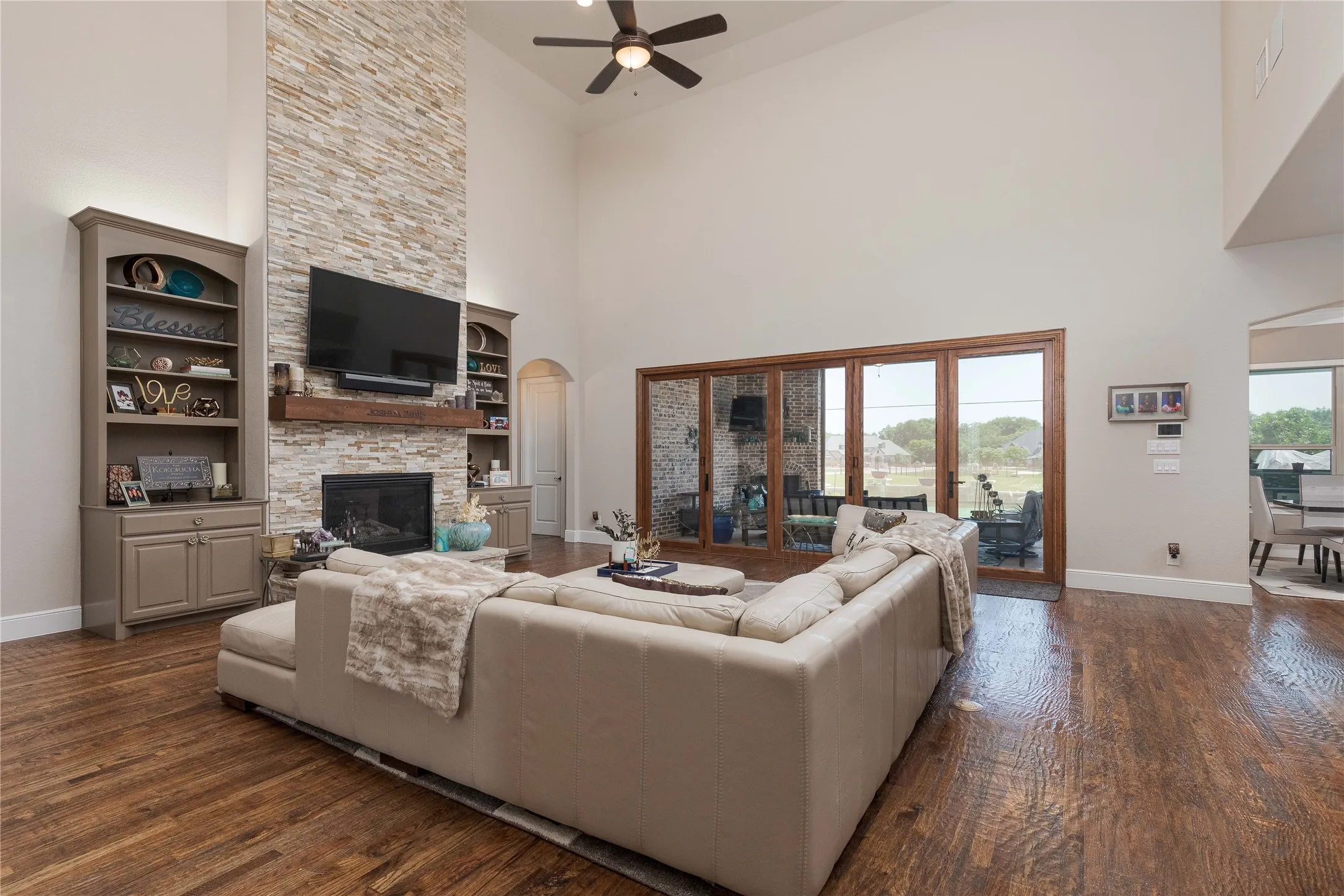 Living area with ceiling fan, a high ceiling, dark wood-style flooring, and a fireplace