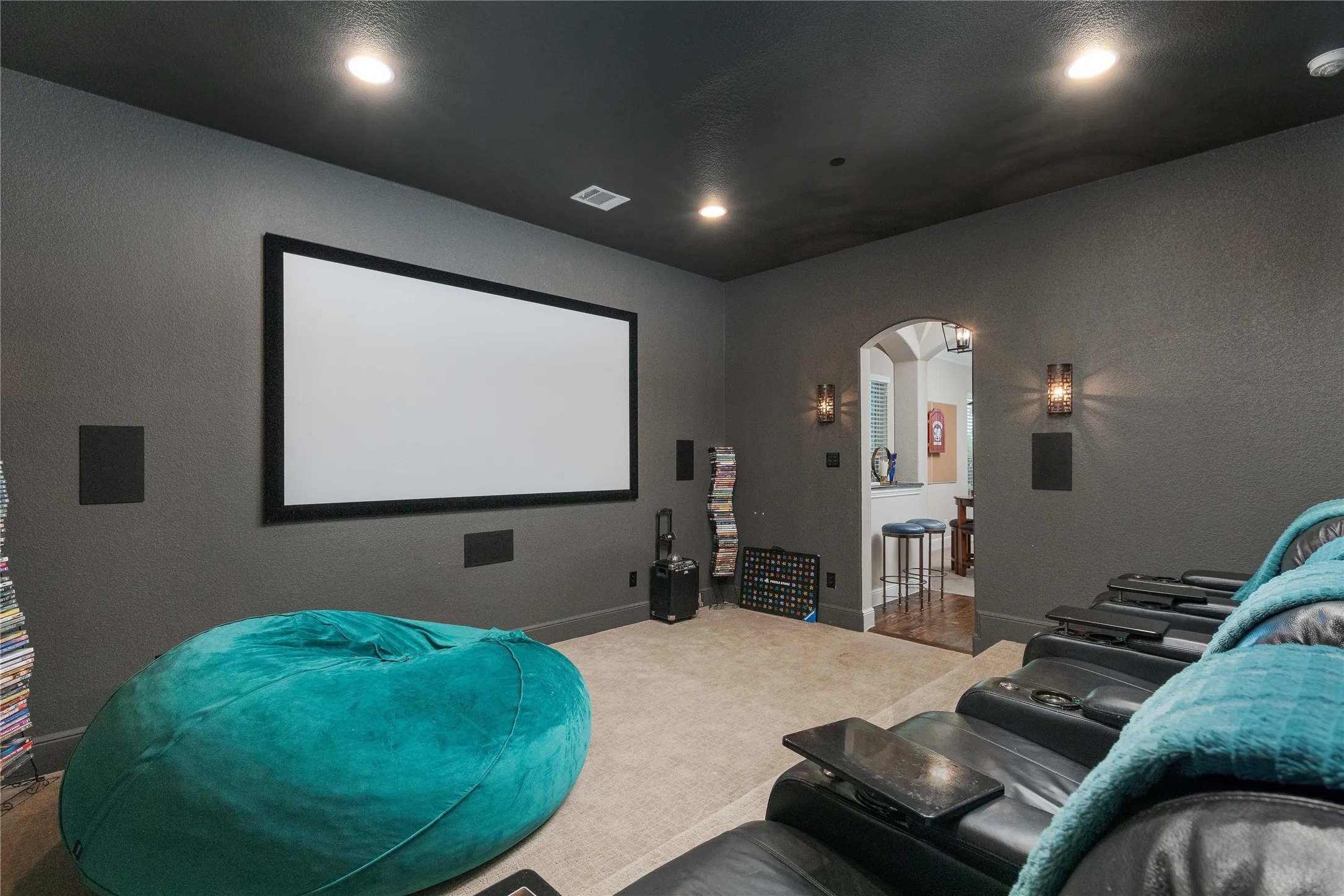 Home theater room with arched walkways, visible vents, baseboards, recessed lighting, and carpet floors