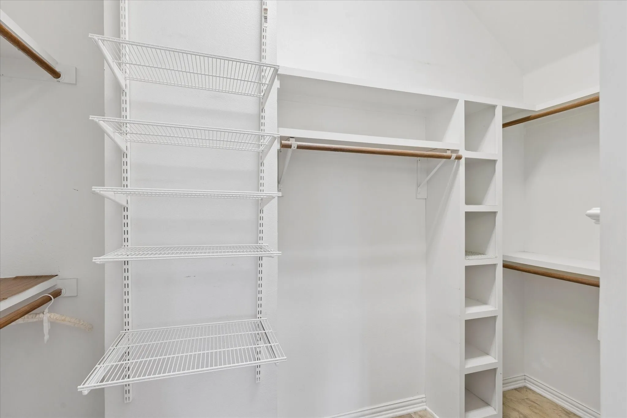 The closet features an extensive organization system, including wire shelving, built-in cubbies, and wooden hanging rods