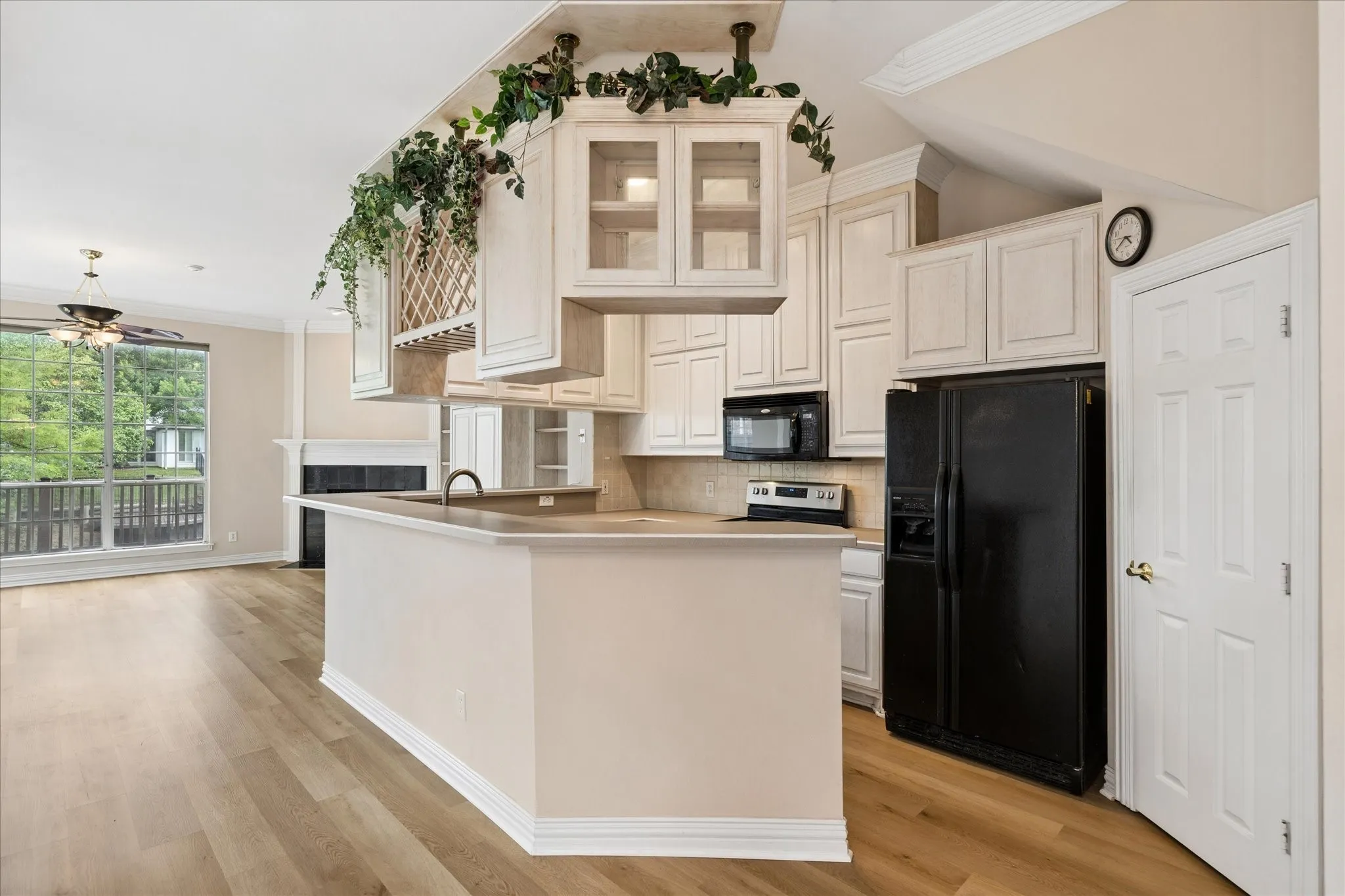 Open concept living space featuring a kitchen with white cabinetry and a breakfast bar, hardwood flooring, and a living area with a fireplace and large windows