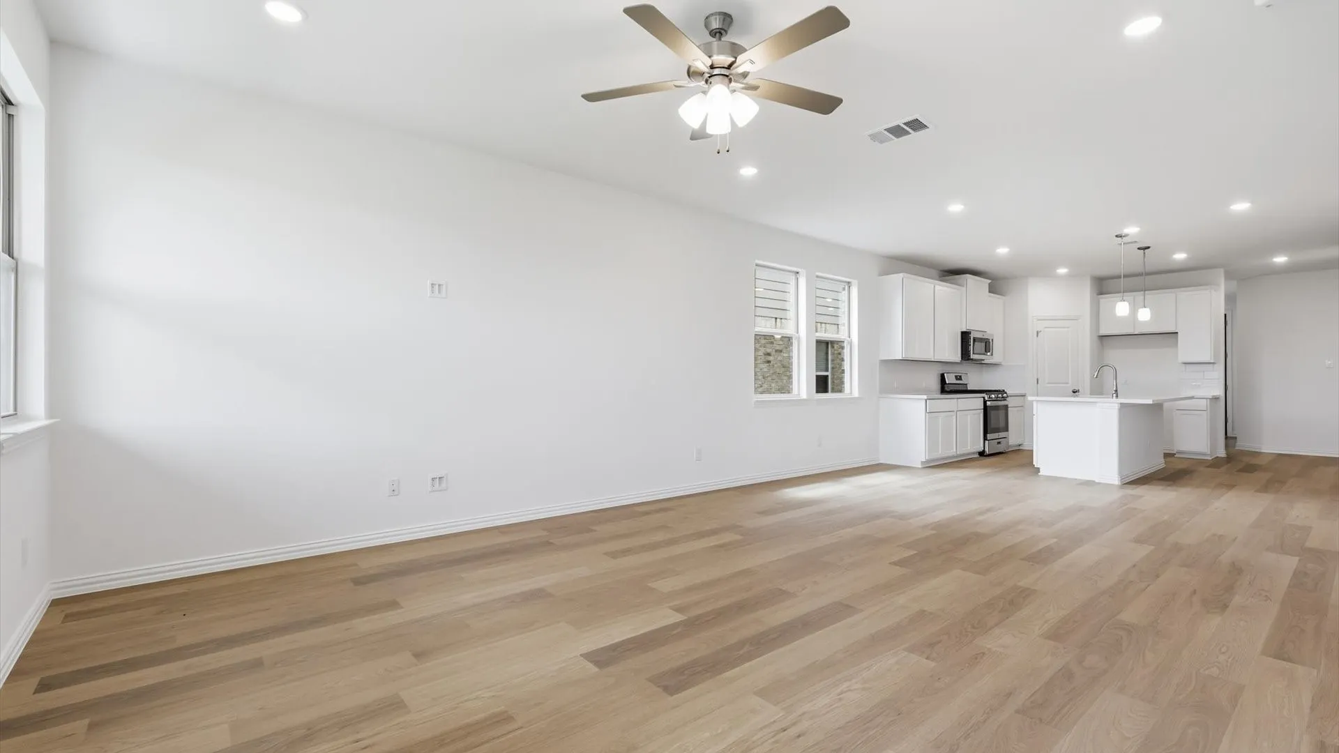 Open-concept living space featuring wood-finish flooring, recessed lighting, and a ceiling fan