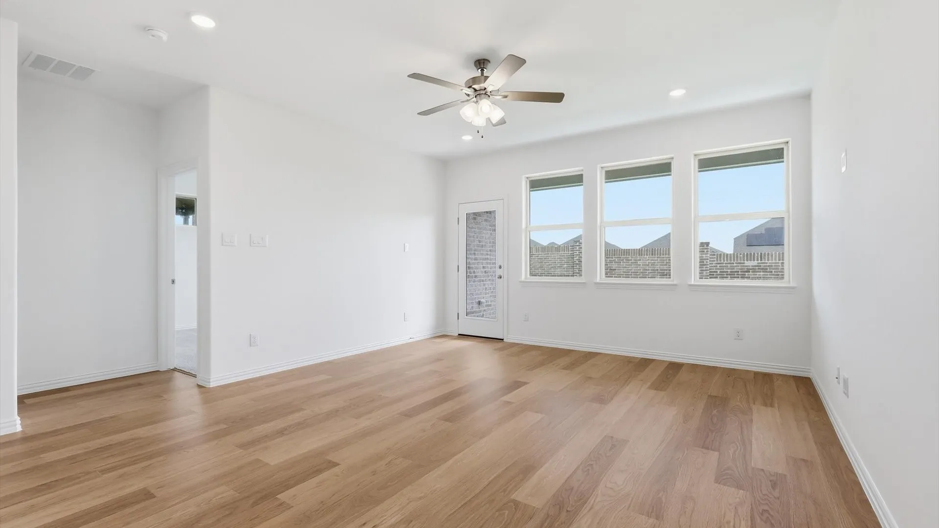 Spacious room featuring wood-finish flooring, recessed lighting, and a ceiling fan