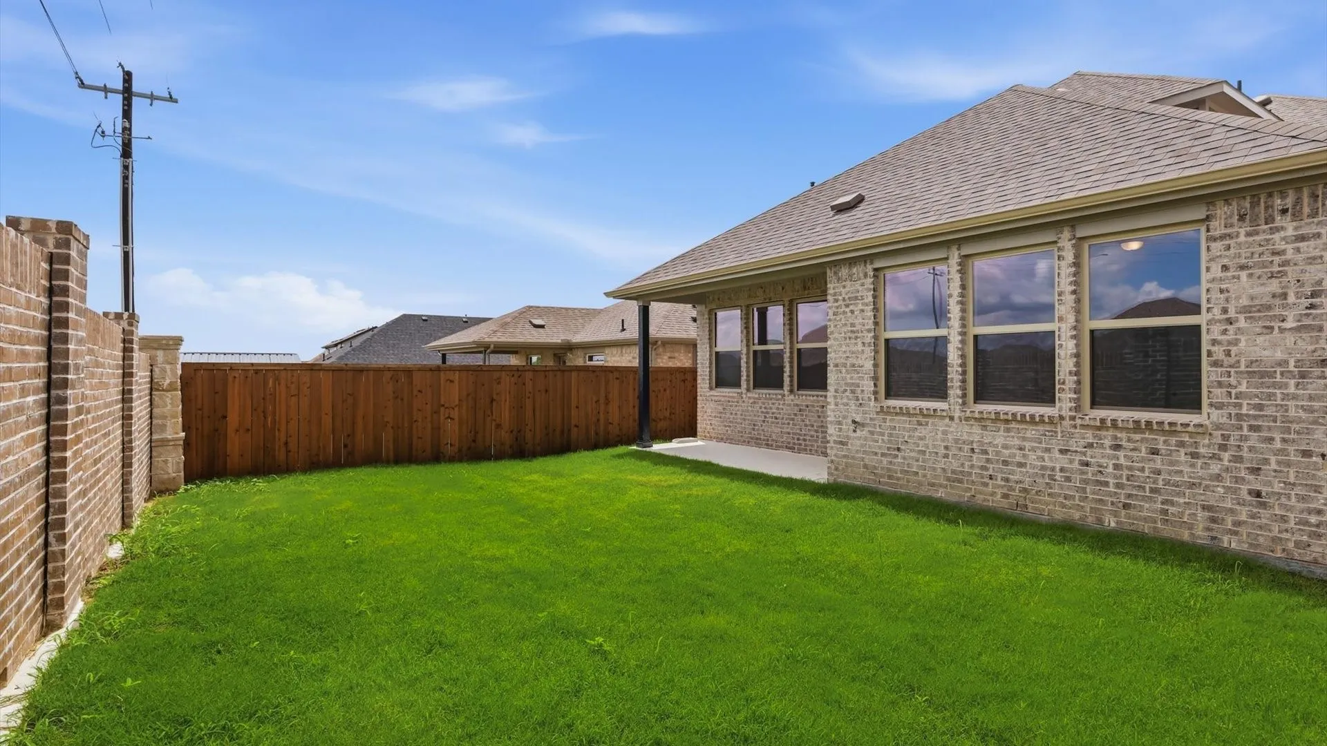 Spacious backyard featuring a lush lawn, privacy fencing, and an extended patio