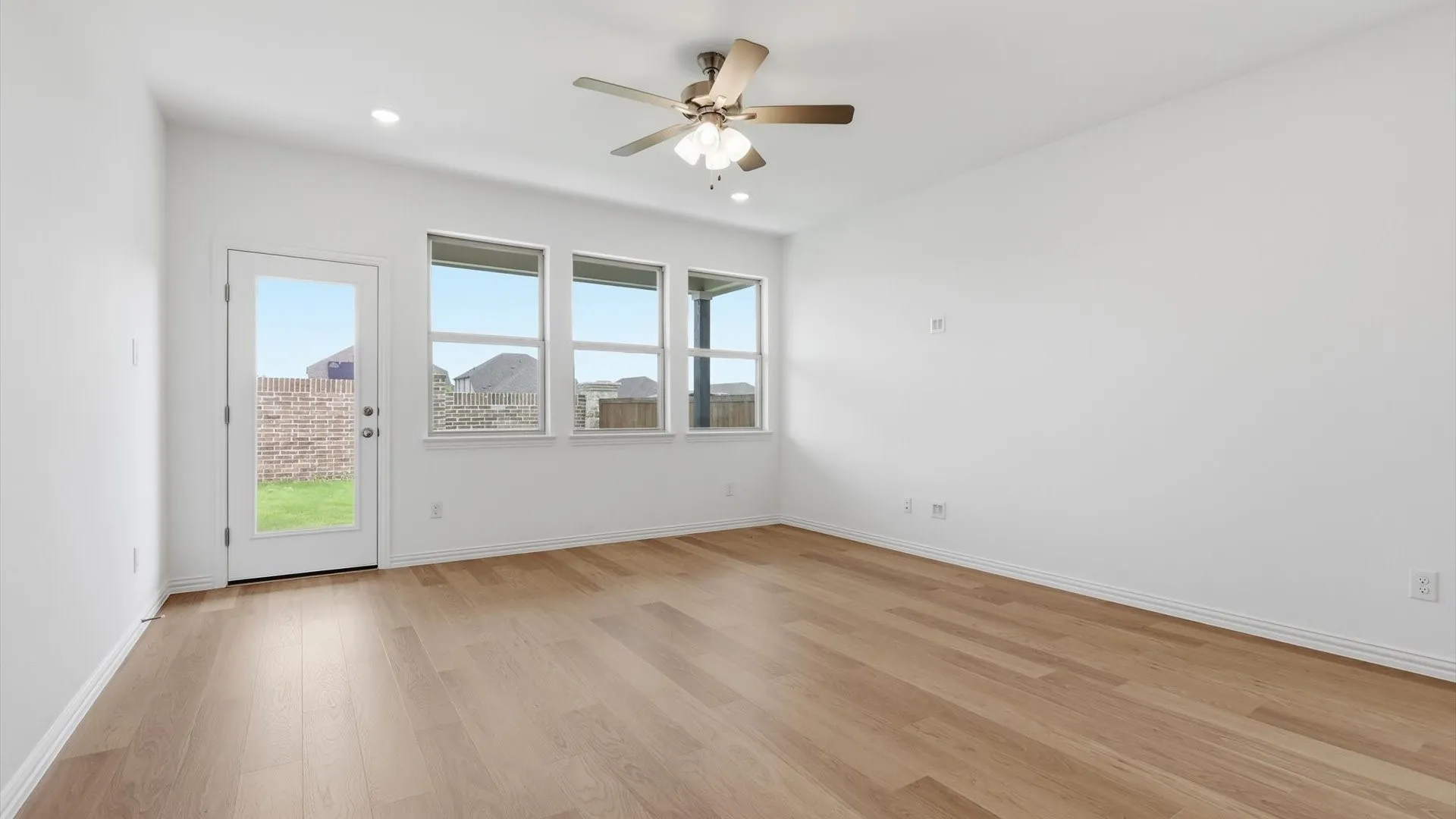Spacious room featuring wood-finish flooring, white baseboards, and a neutral wall palette