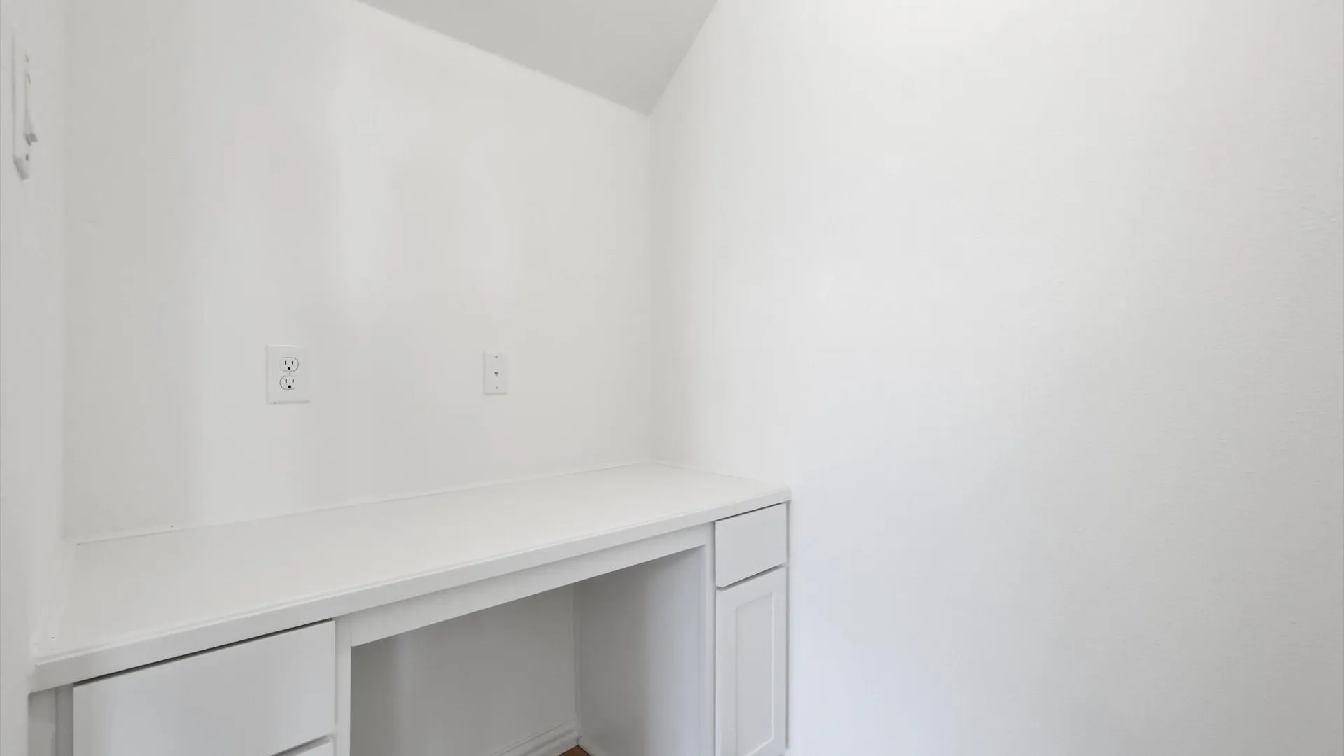 Integrated white built-in desk featuring a solid surface countertop and multiple electrical outlets