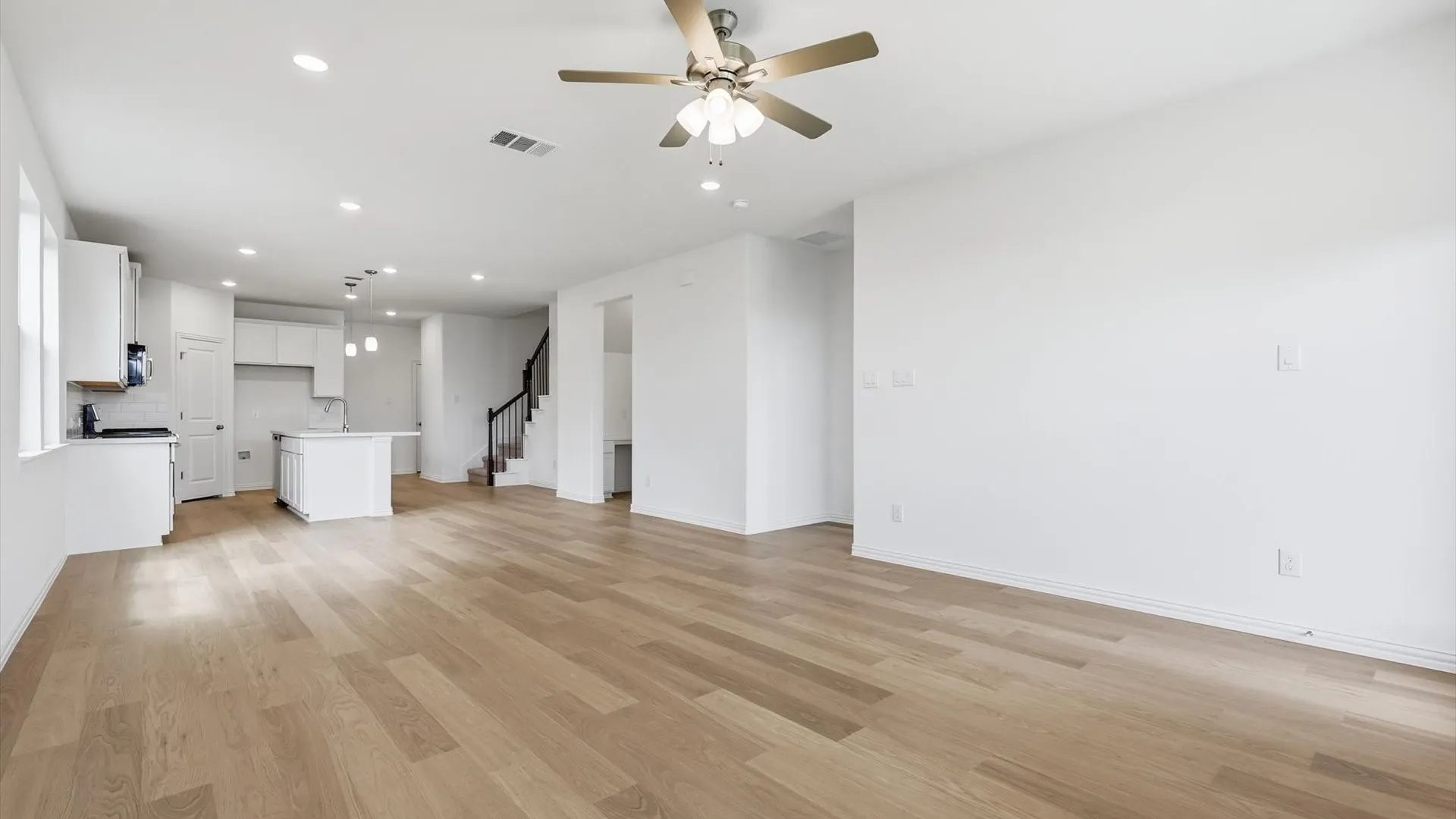 Open-concept living area featuring wood-finish flooring, recessed lighting, and a ceiling fan