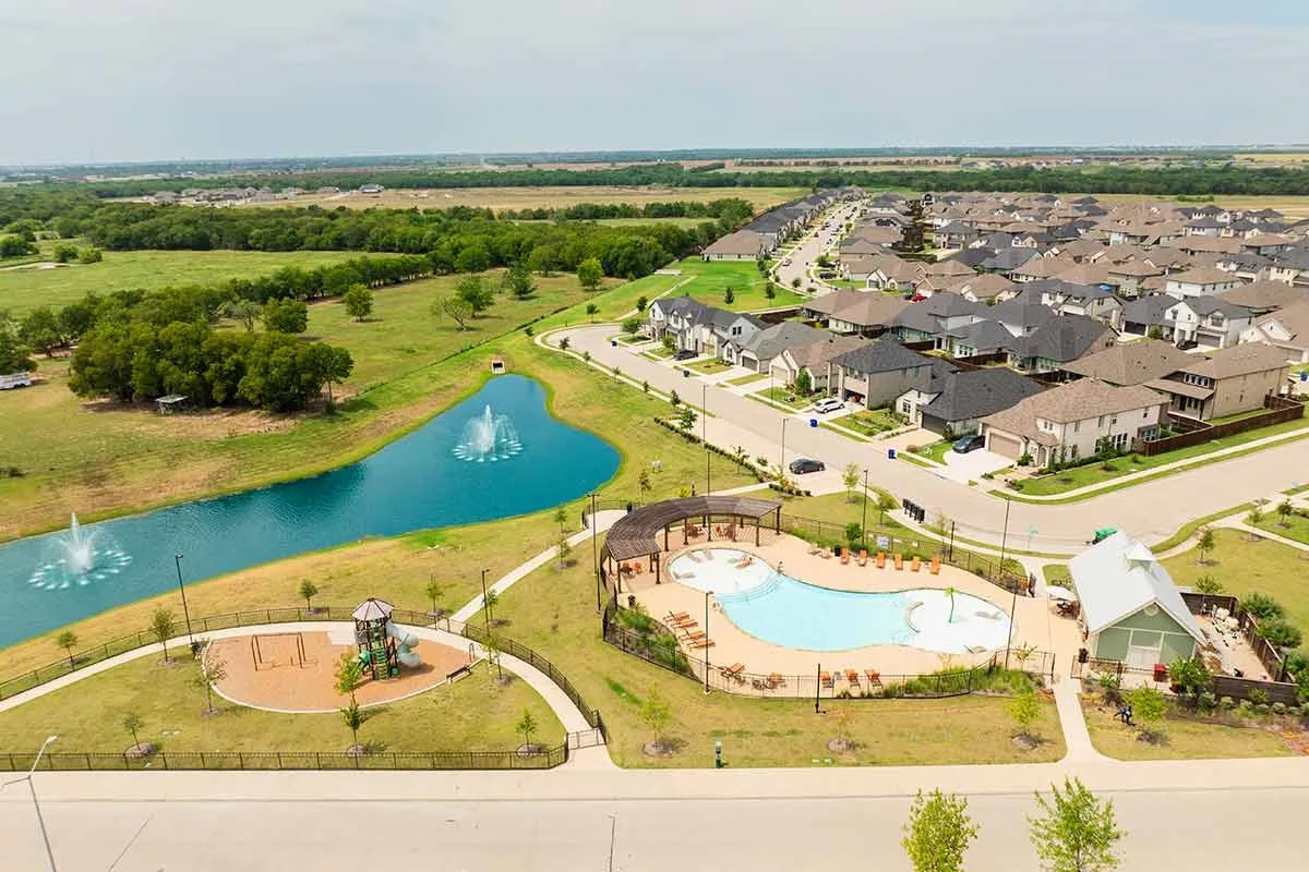 Community with a central pond featuring two fountains, a children's play area, and an outdoor swimming pool with surrounding lounge space
