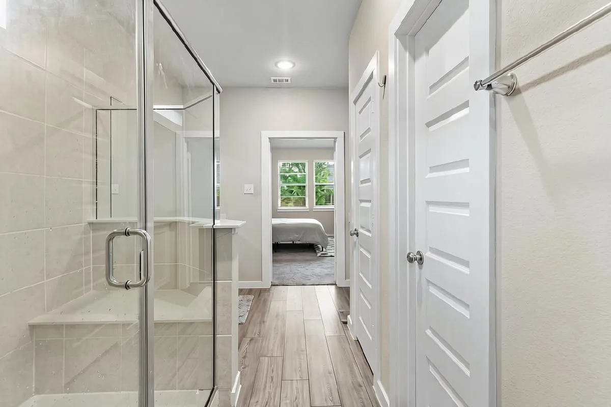 Glass-enclosed shower with a built-in bench, wood-finish flooring, recessed lighting, and white interior doors