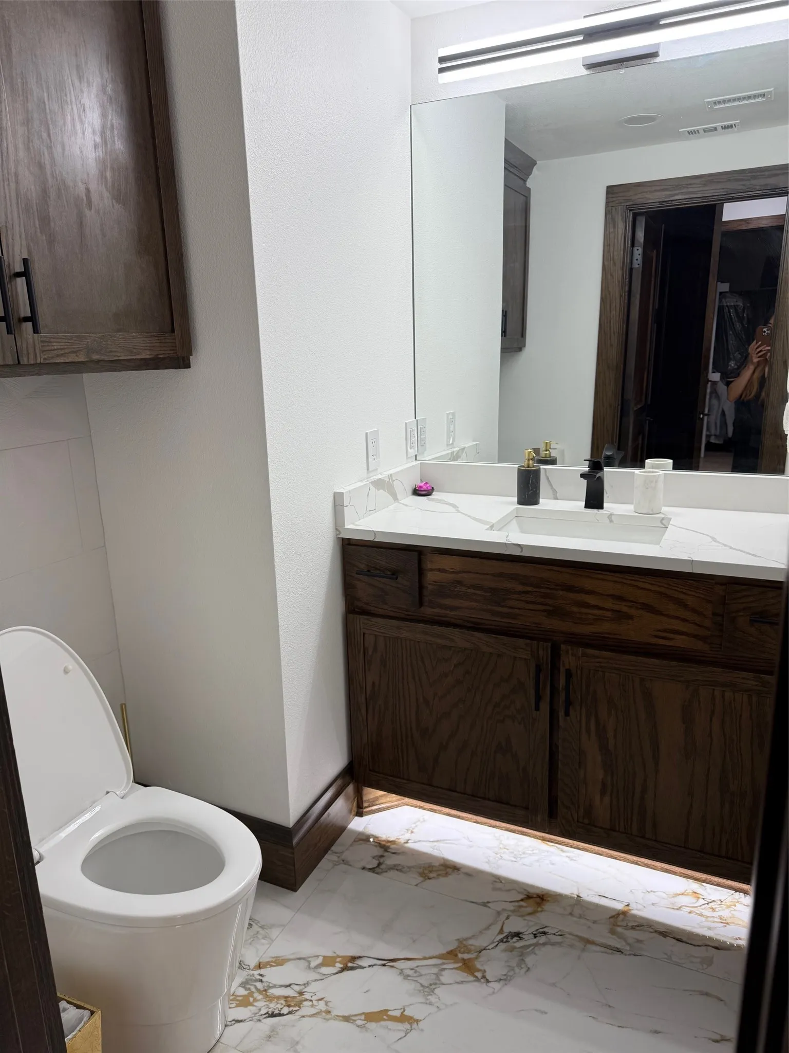Half bathroom with light marble finish flooring and vanity