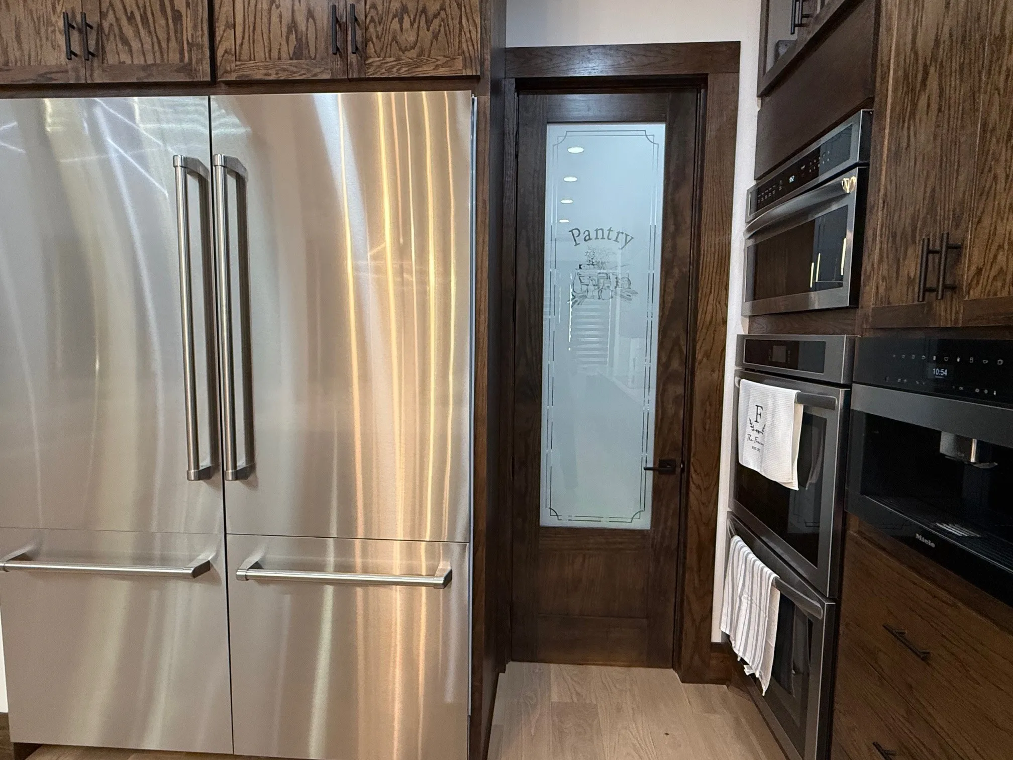 Kitchen featuring appliances with stainless steel finishes, light wood-style flooring, and dark brown cabinetry