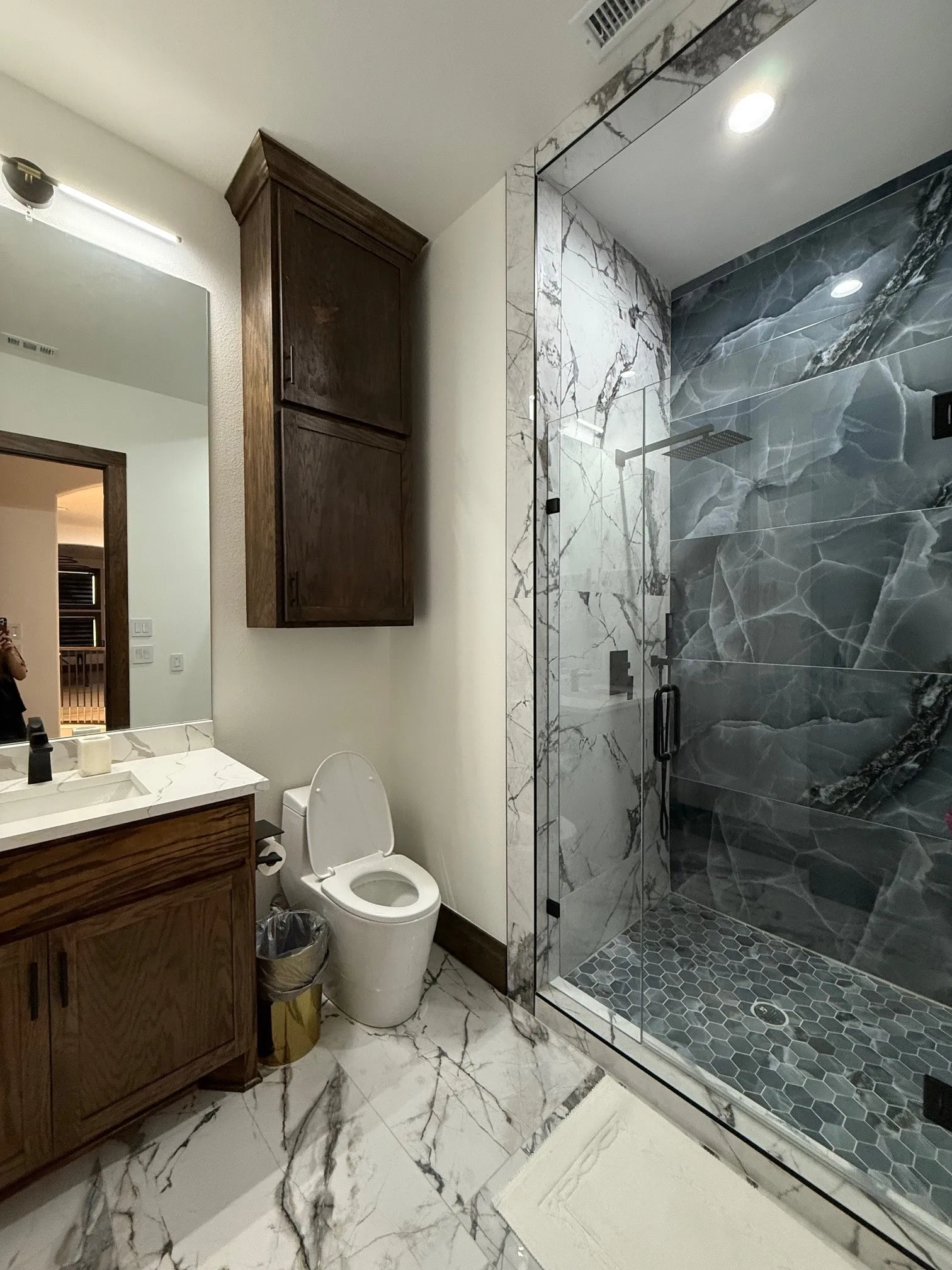 Full bath with light marble finish floors, a marble finish shower, and vanity