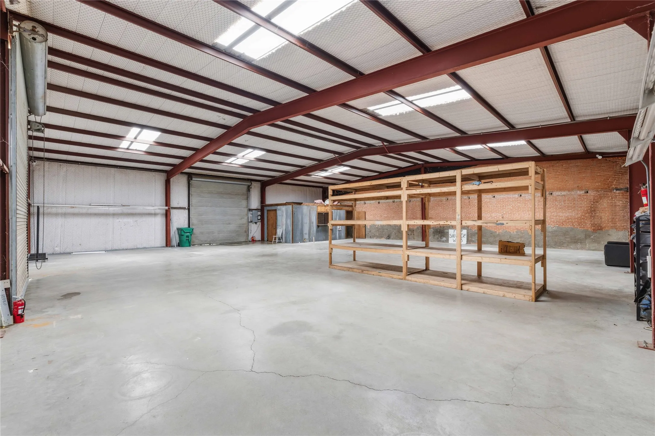Expansive warehouse space featuring a high ceiling with exposed metal beams, skylights, and a concrete floor
