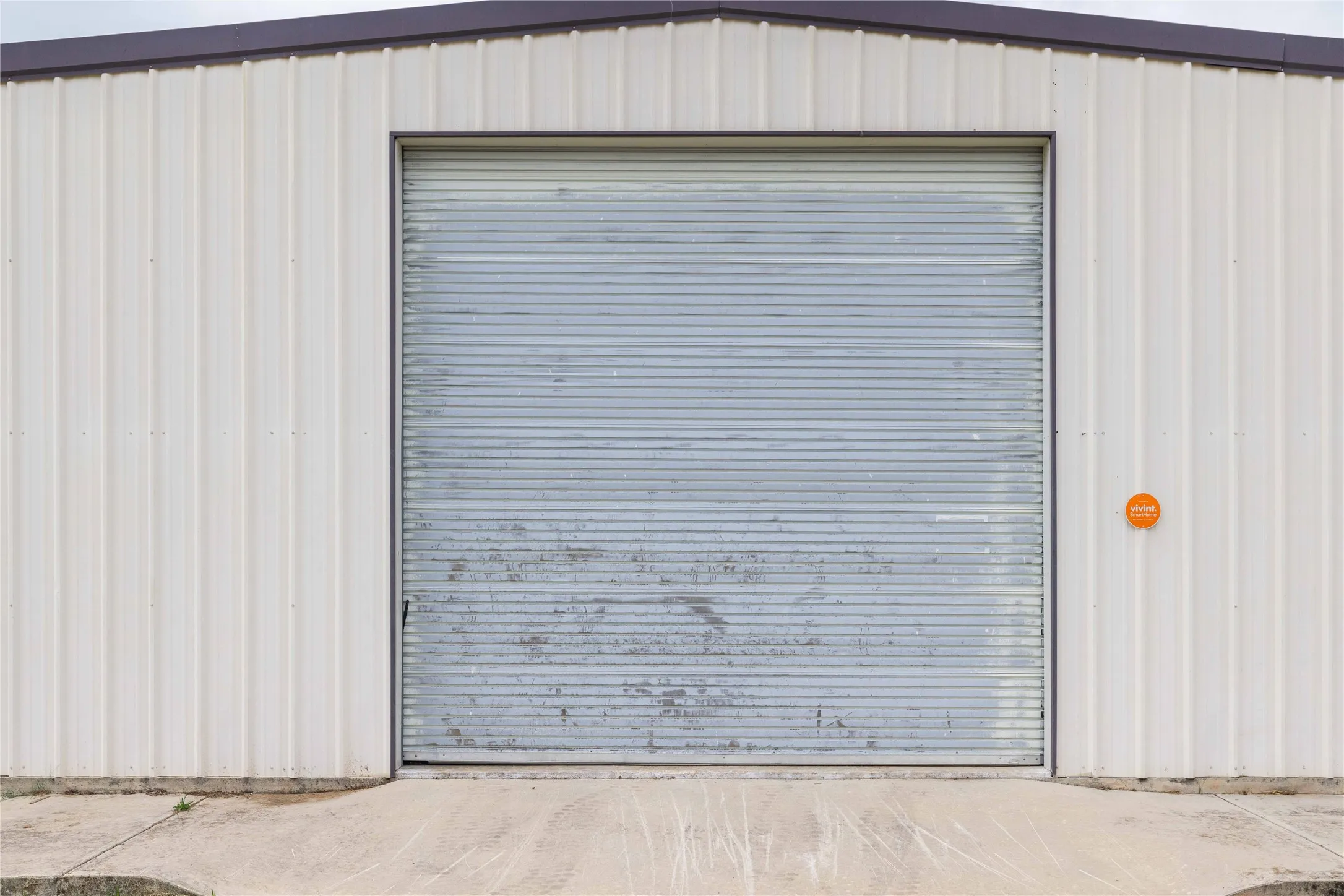 The property features a large roll-up door, metal siding, and a concrete approach