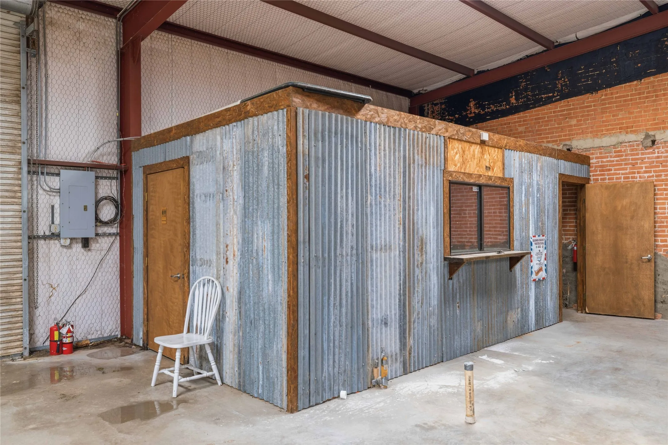 This property features an interior structure with corrugated metal siding, two wooden doors, and a service window