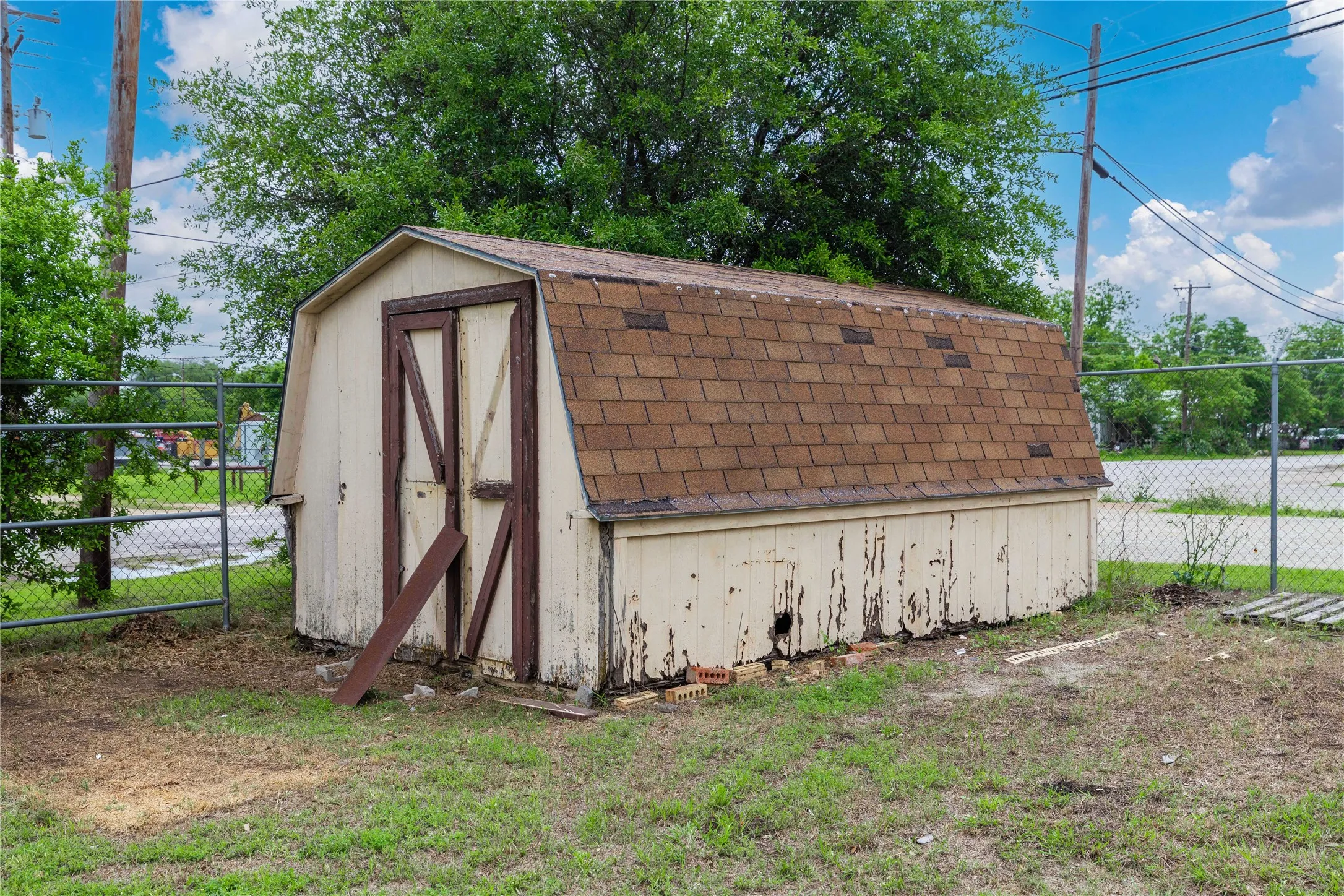The property includes an outdoor storage shed with a gambrel roof and a fenced yard area