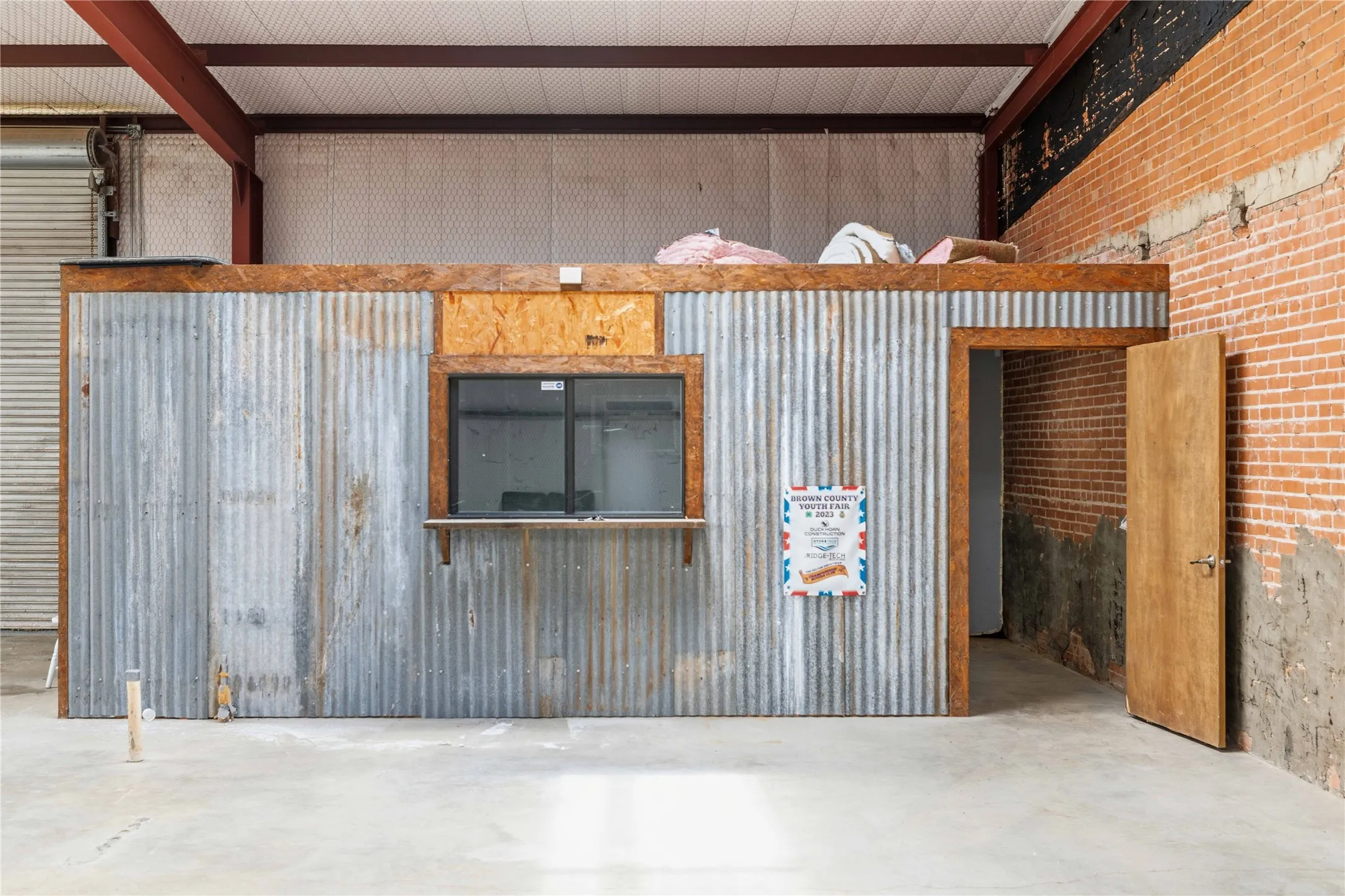 The property features an interior structure with corrugated metal siding, a service window, and a wooden door
