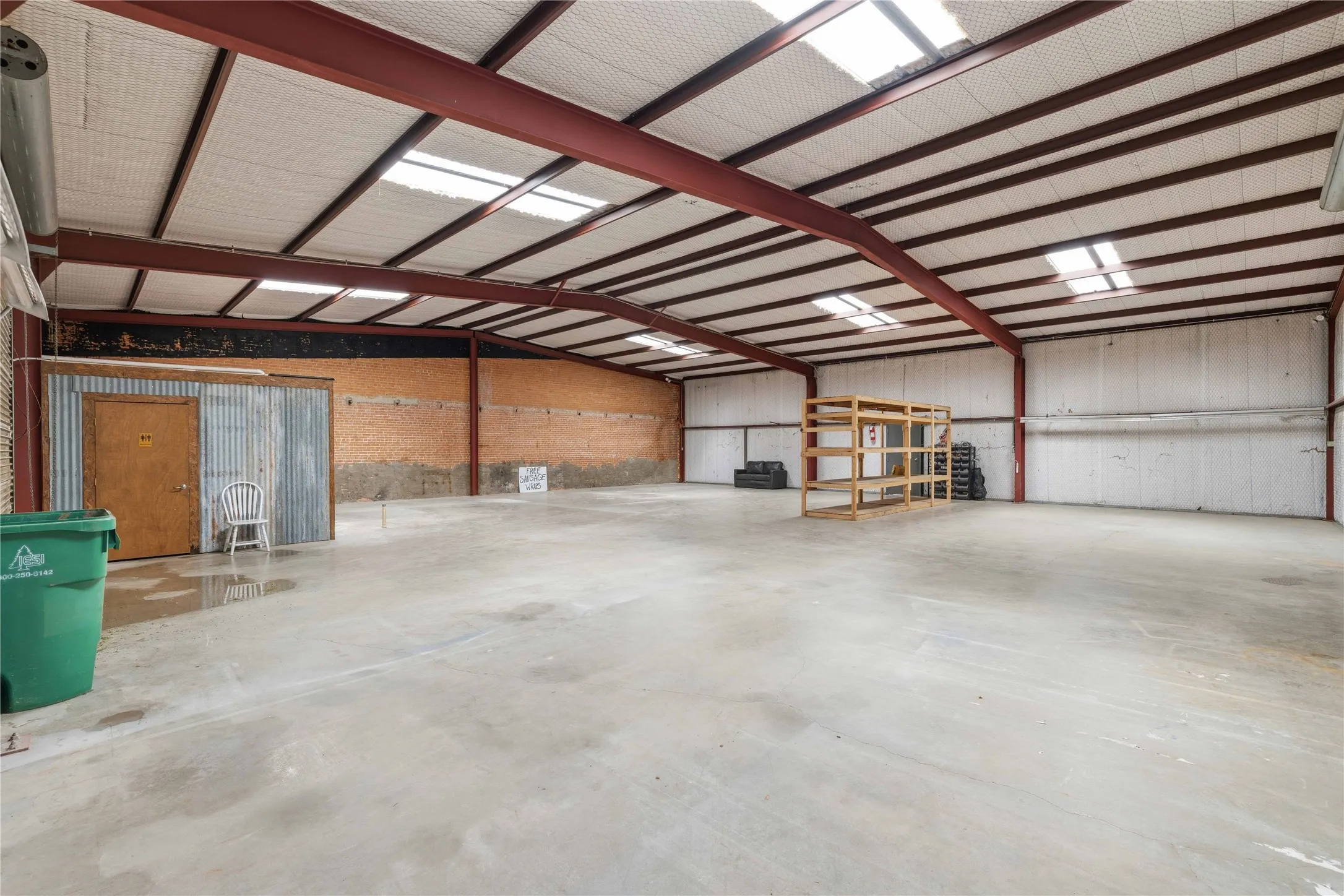 Spacious open-concept commercial interior featuring skylights, exposed metal beams, and concrete flooring