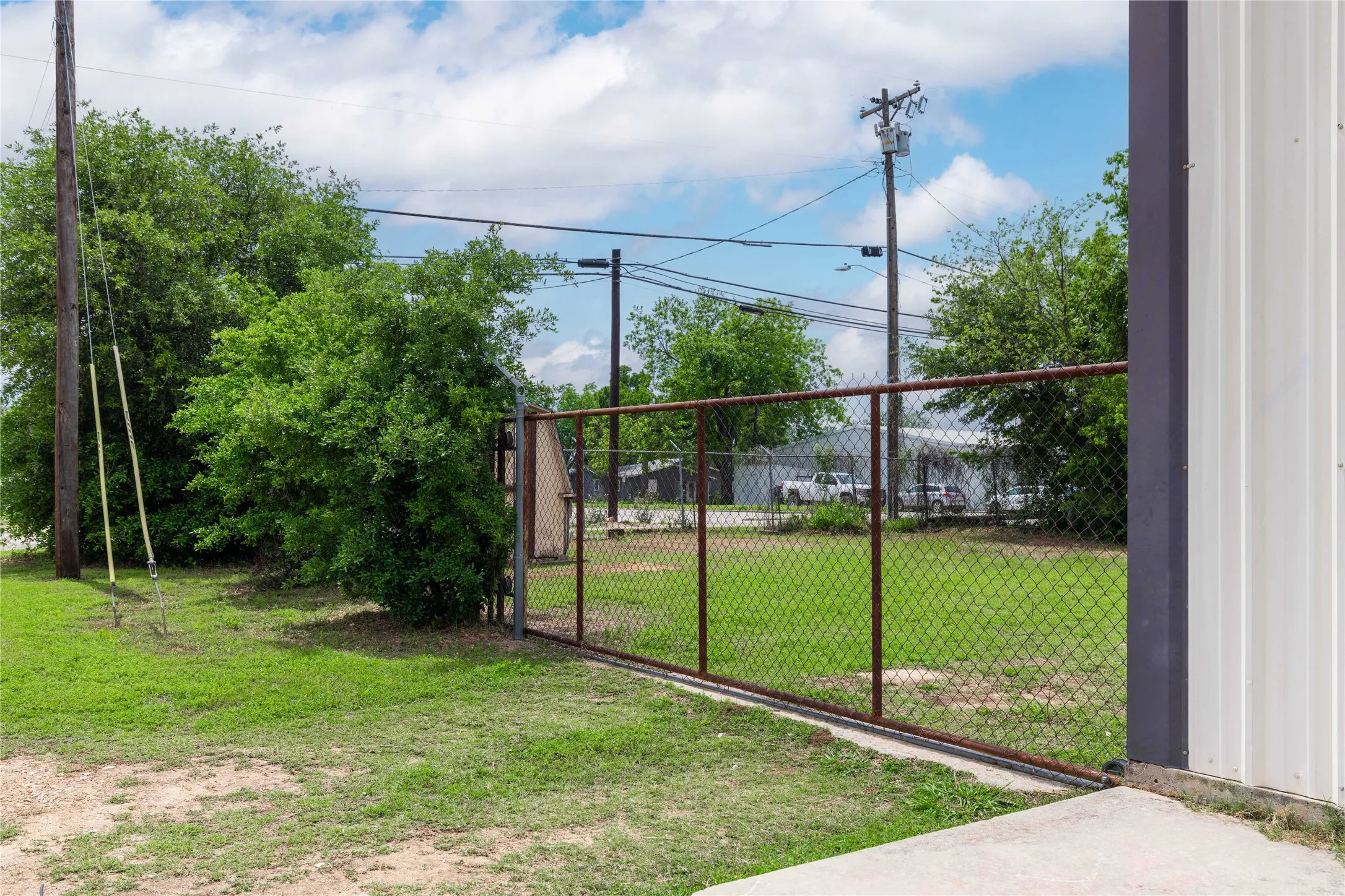 The property features a chain-link fence, a well-maintained lawn, and mature trees