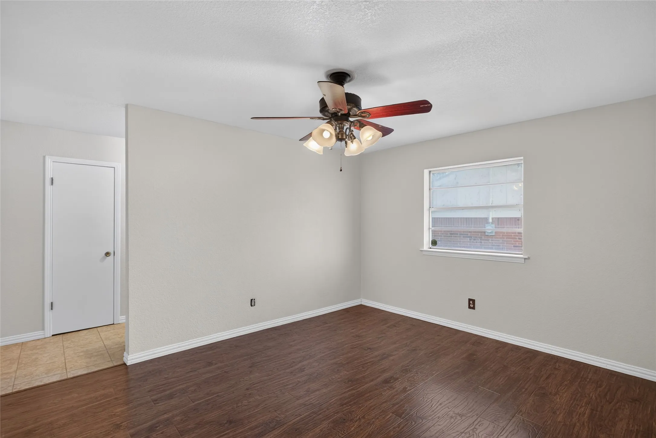 Room featuring wood-finish flooring, light neutral wall paint, and white baseboards