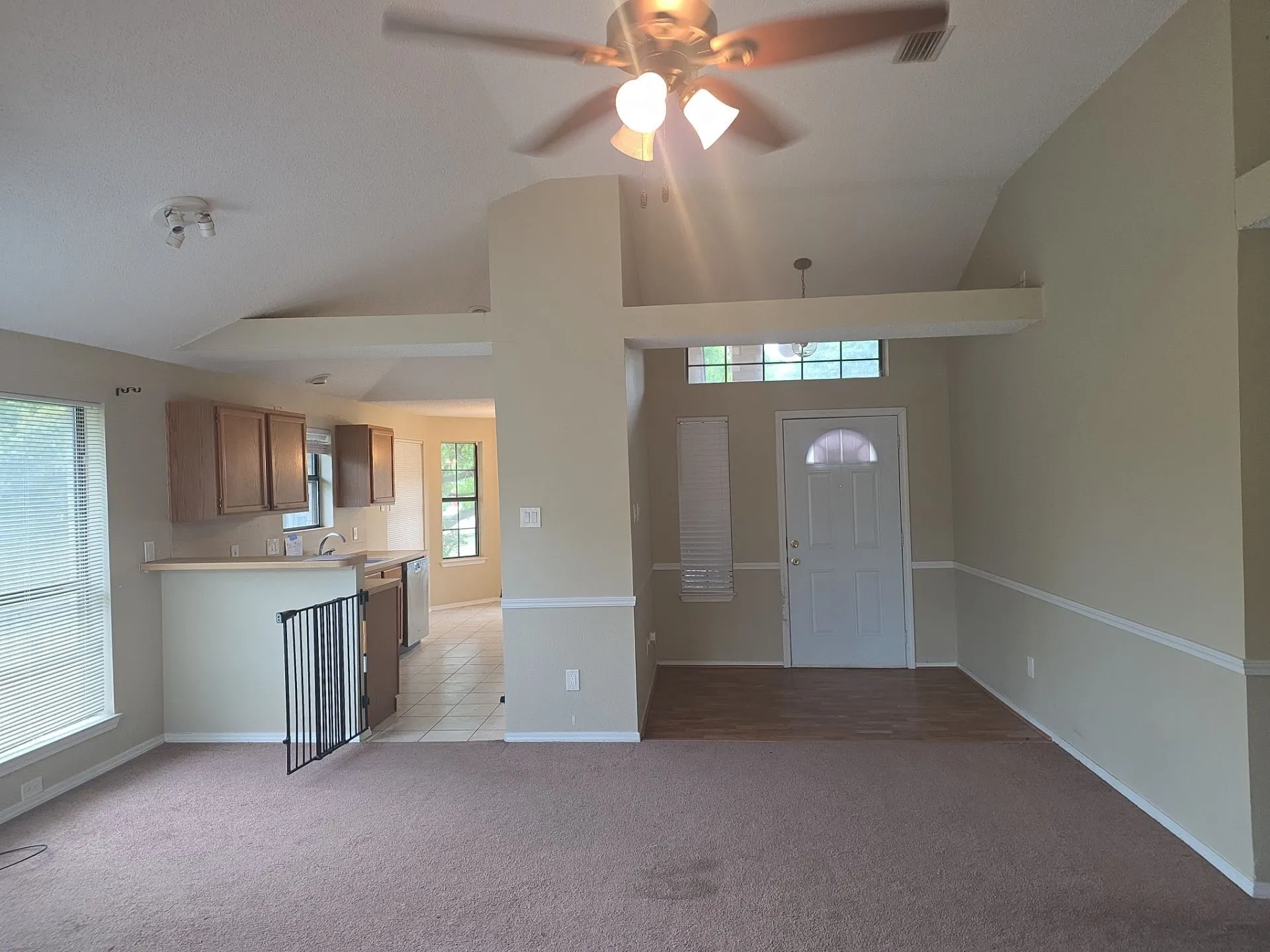The main living area features vaulted ceilings, a ceiling fan, and carpeted flooring