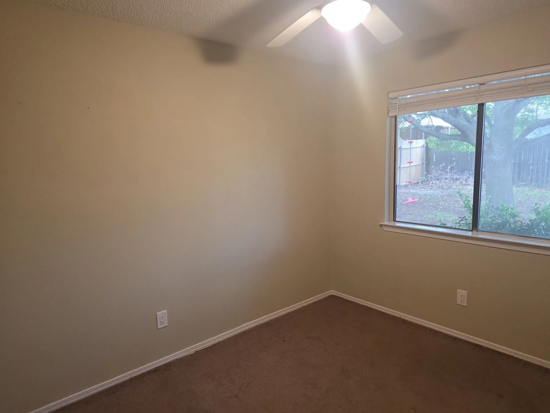 This room features a window providing natural light, a ceiling fan, and carpeted flooring