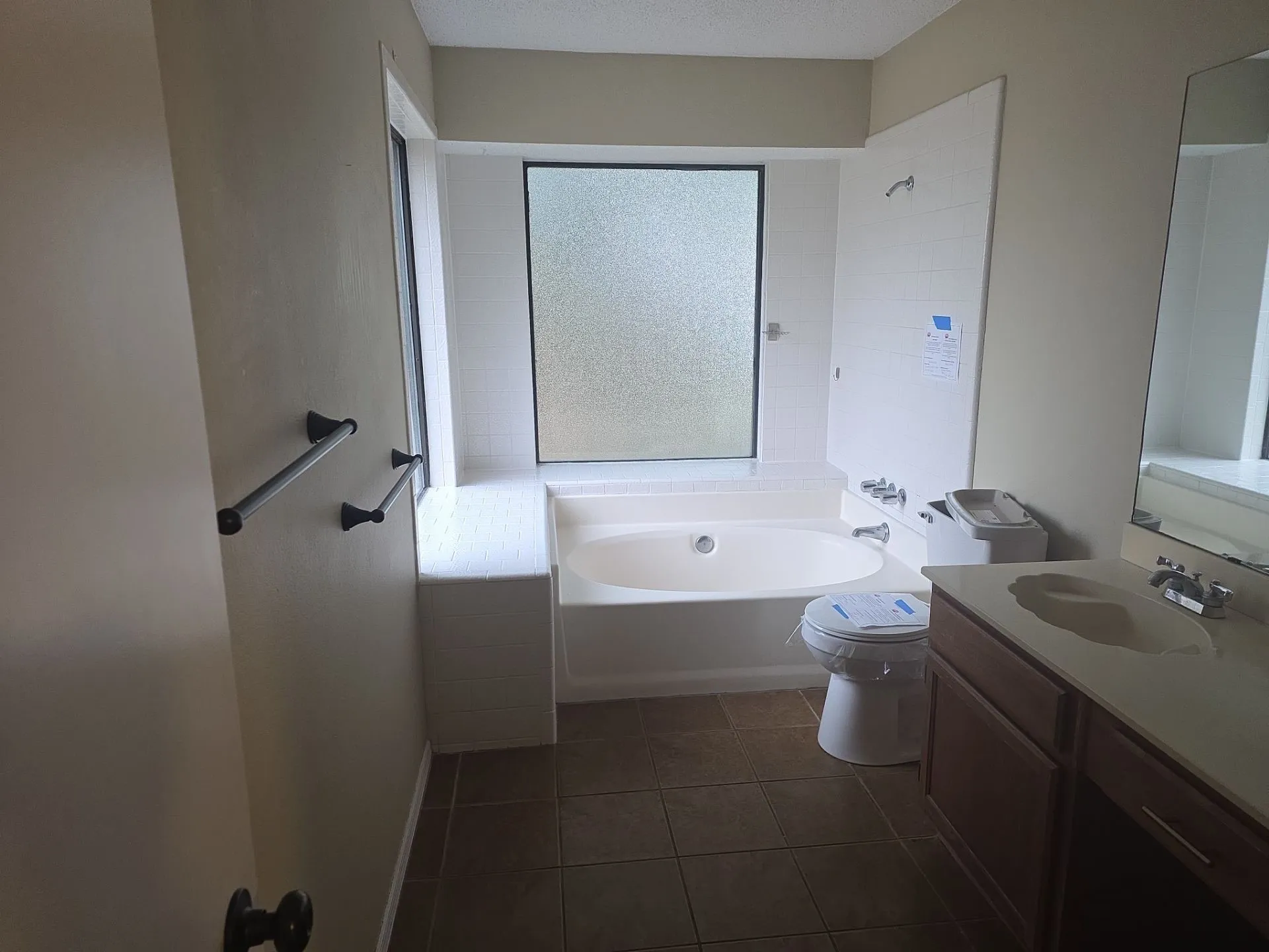 Bathroom featuring a built-in bathtub with tiled surround, a frosted glass window, and a vanity with an integrated sink
