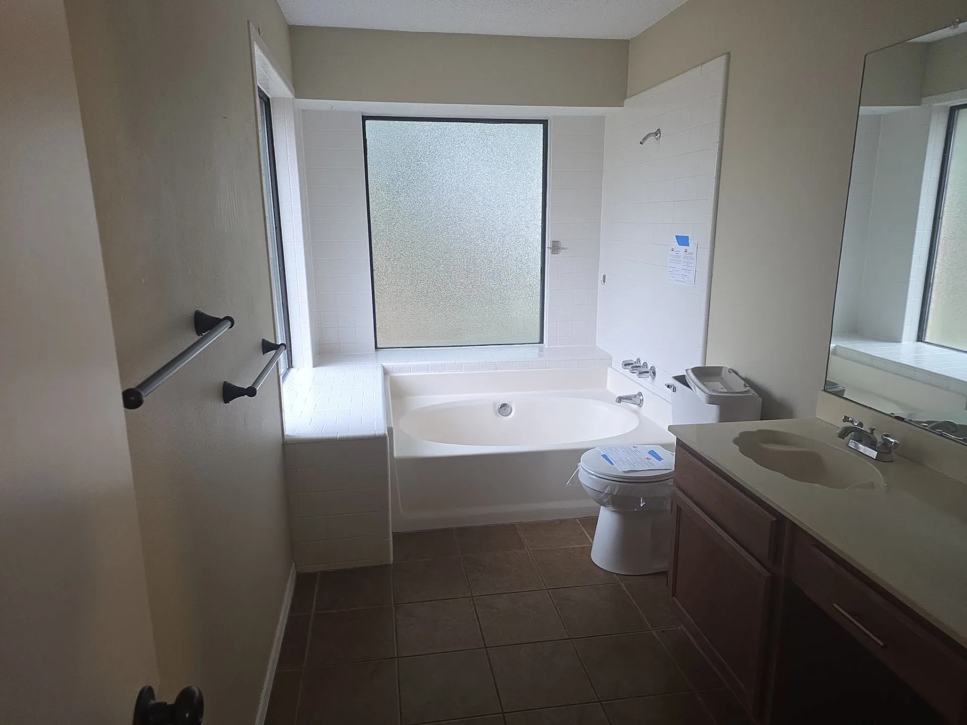 The bathroom features a built-in bathtub, a window with privacy glass, and a vanity with a sink and storage cabinetry
