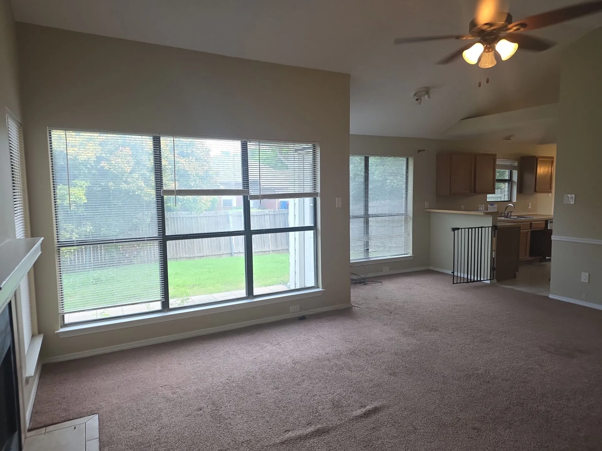 Living area with vaulted ceilings, a ceiling fan, and carpeted flooring