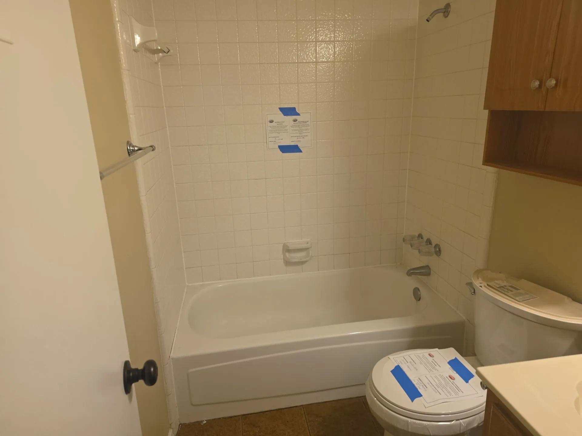 Bathroom with a white bathtub and white tiled walls, featuring a chrome shower head and faucet