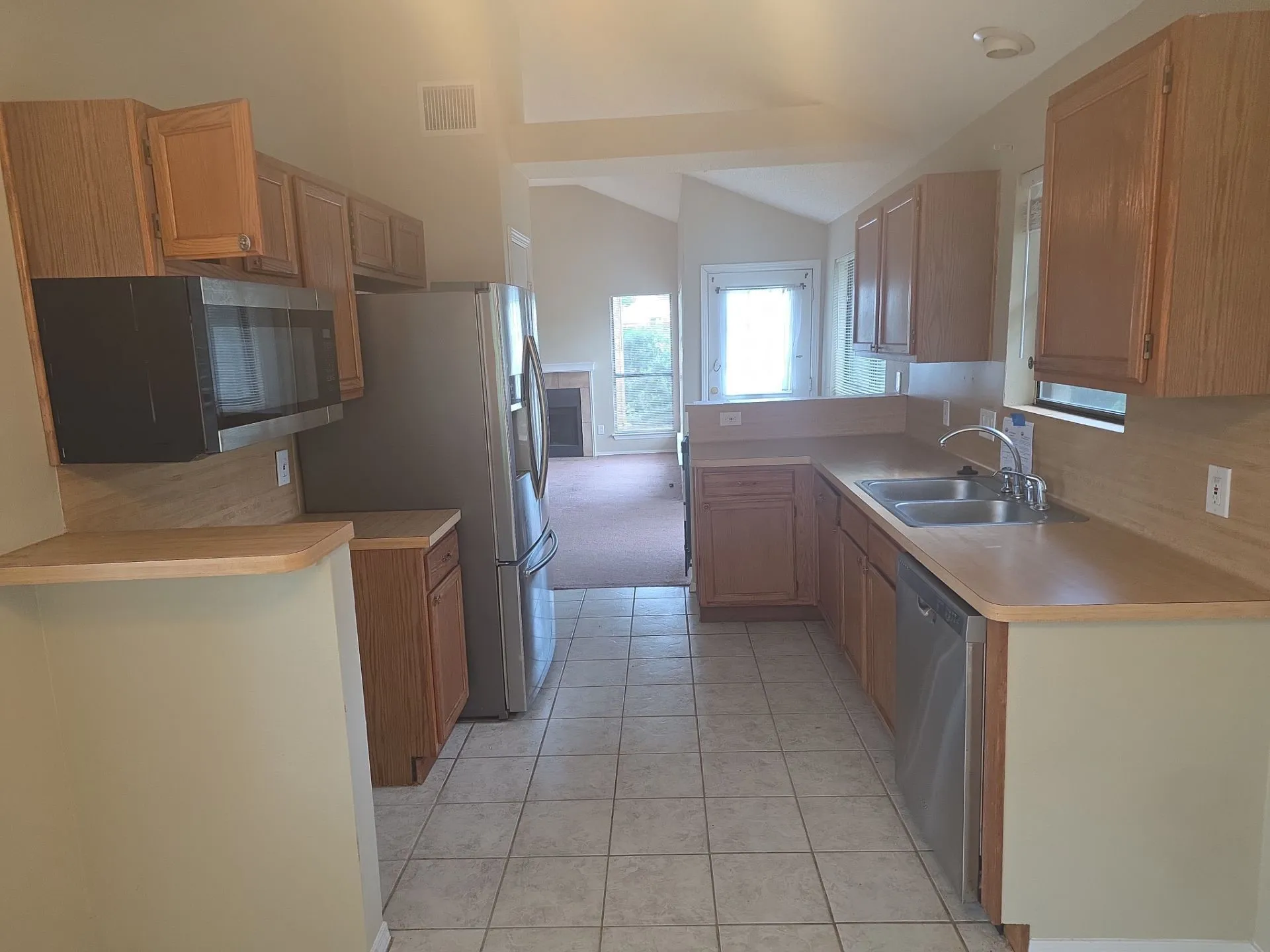 The kitchen features wood cabinetry, a stainless steel refrigerator, and a stainless steel microwave