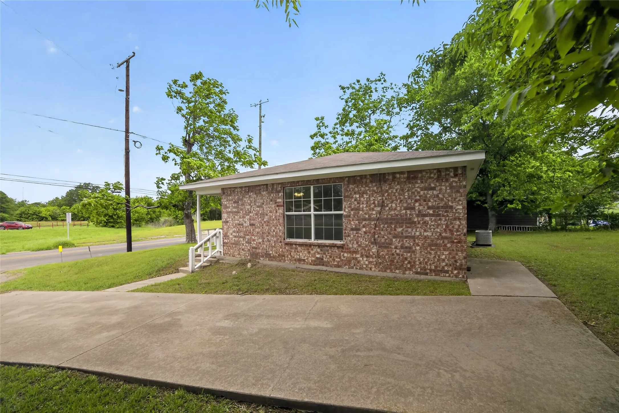 The property features a brick exterior with a pitched roof, a concrete driveway, and a well-maintained lawn