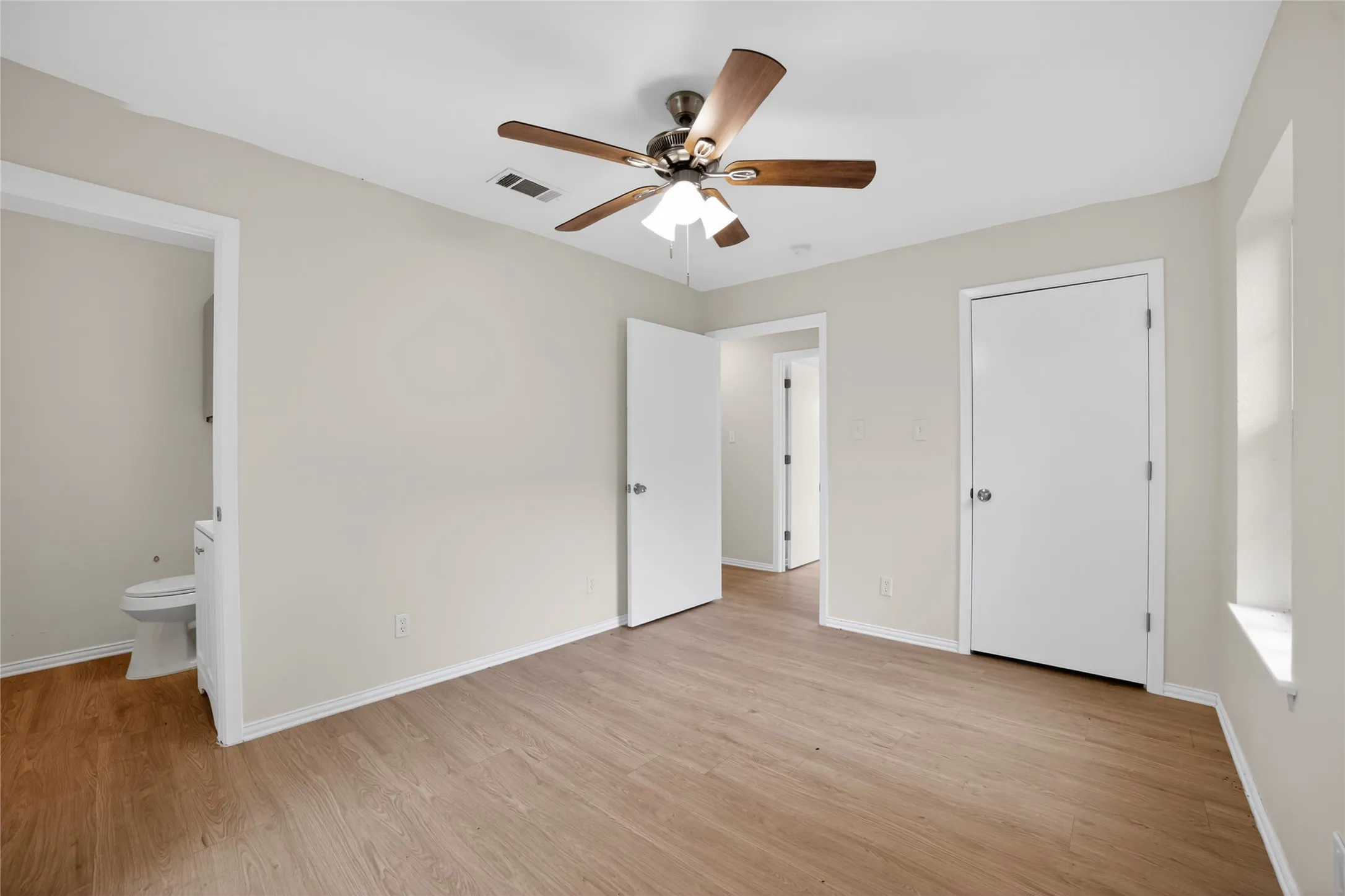 This room features light wood-look flooring, neutral wall paint, and a ceiling fan with integrated lighting
