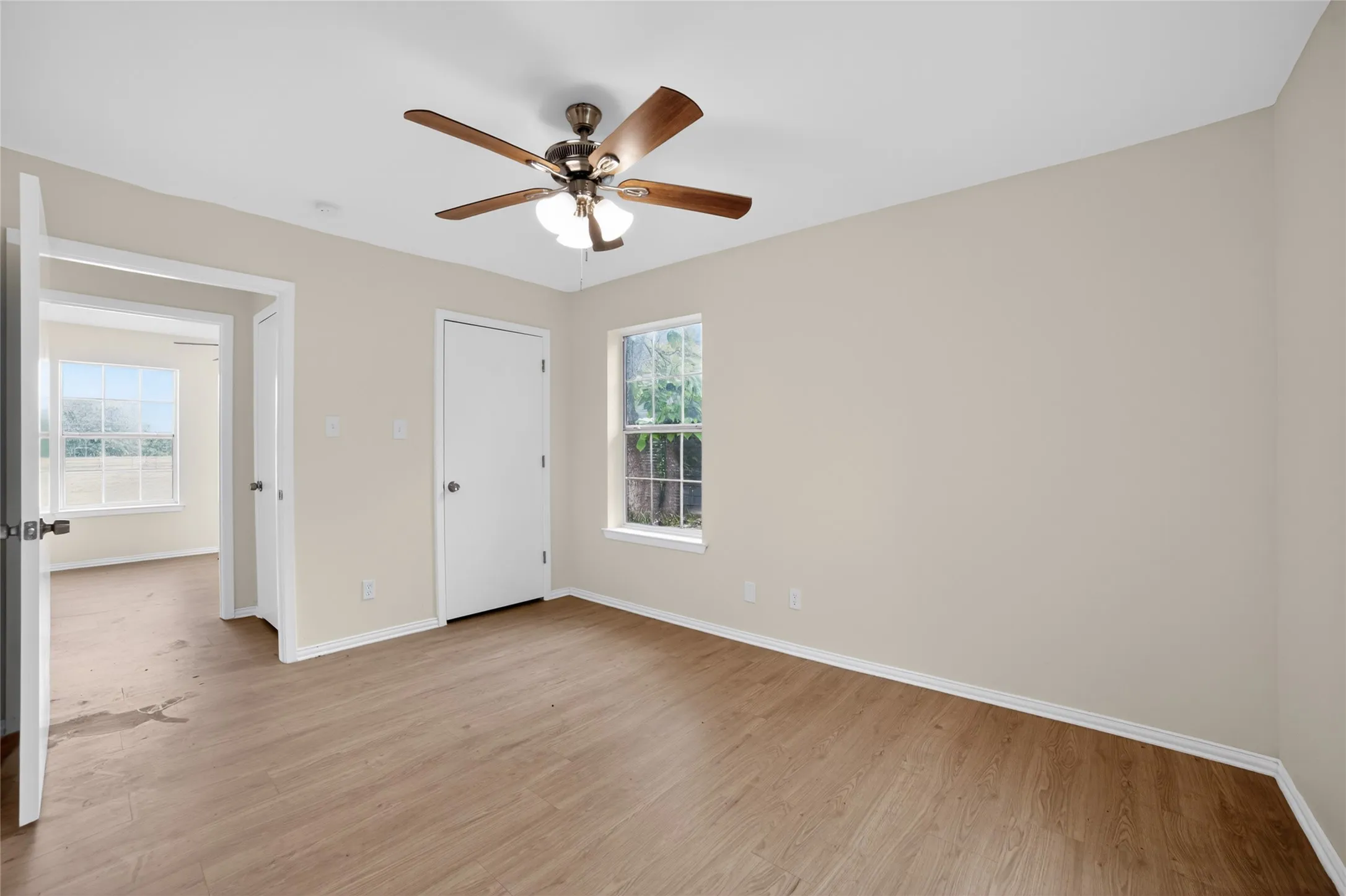 Room featuring light wood-style flooring, a window providing natural light, and a ceiling fan with integrated lighting