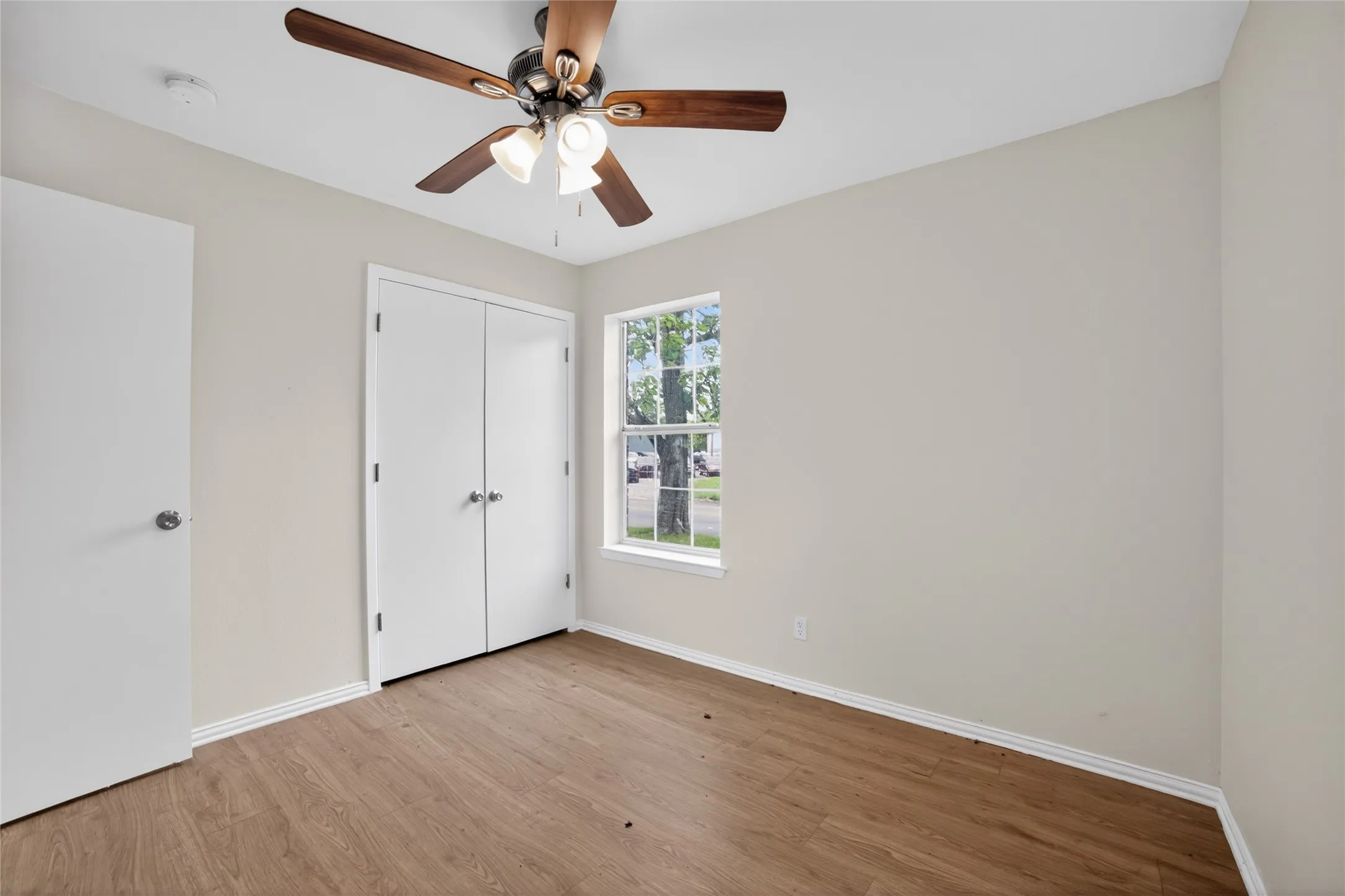 This room features wood-look flooring, a window providing natural light, and a ceiling fan with integrated lighting