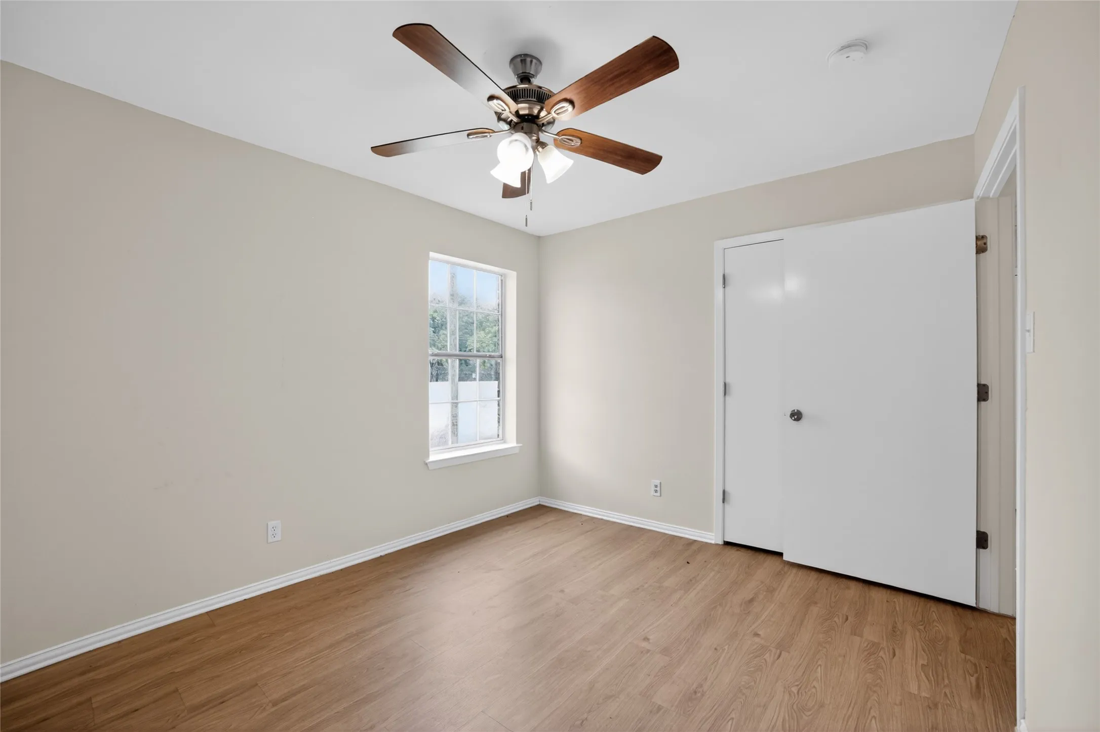 This room features light-colored walls, a window providing natural light, and wood-look flooring
