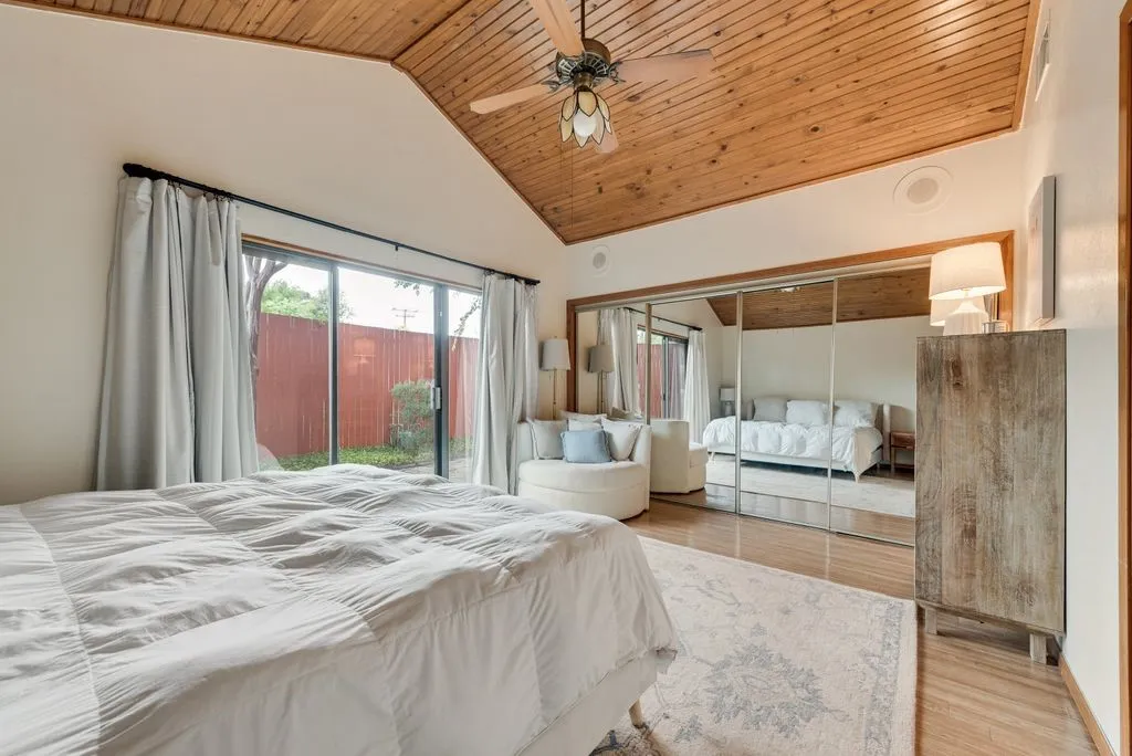The primary bedroom features vaulted wood ceilings and direct access to the private outdoor patio.