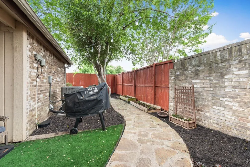A stone pathway winds through the private yard, complemented by low-maintenance turf and a fully fenced yard.