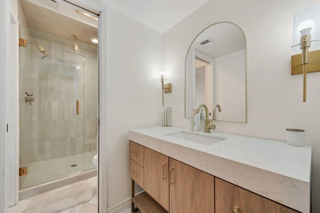 The opposite side of the ensuite includes a separate single vanity, glass-enclosed shower, and private toilet area.