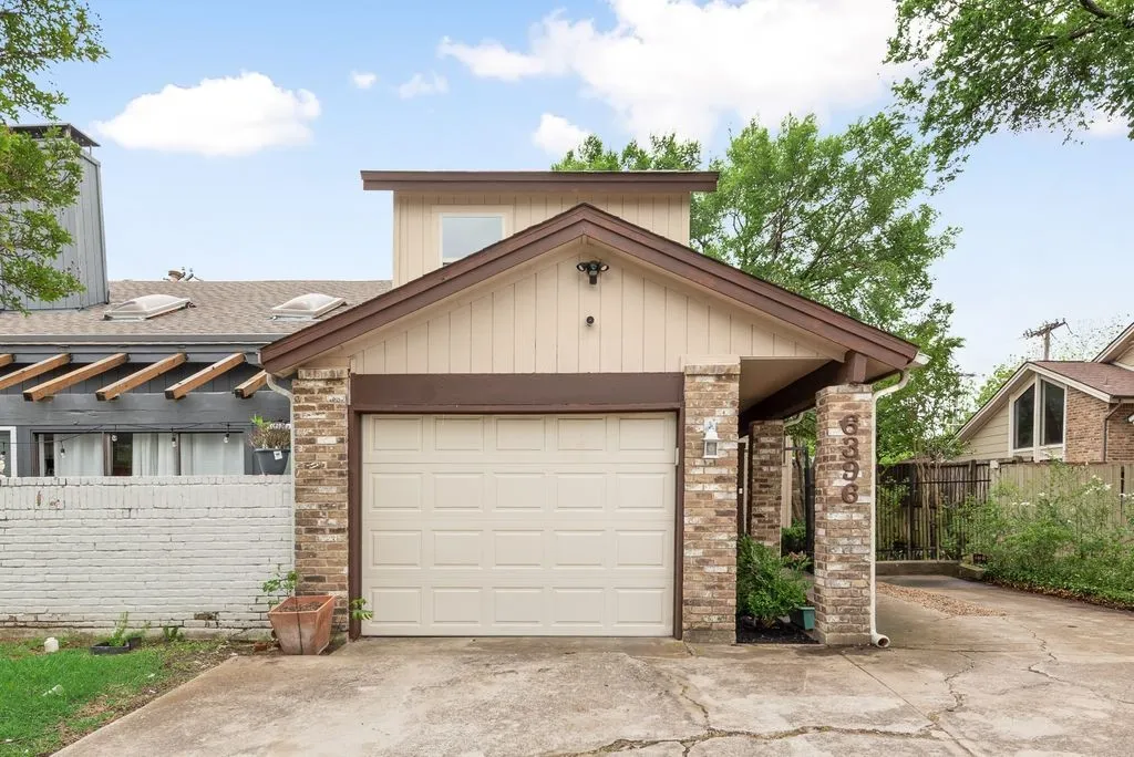 A clean driveway and attached garage provide practical access with a polished exterior presentation.