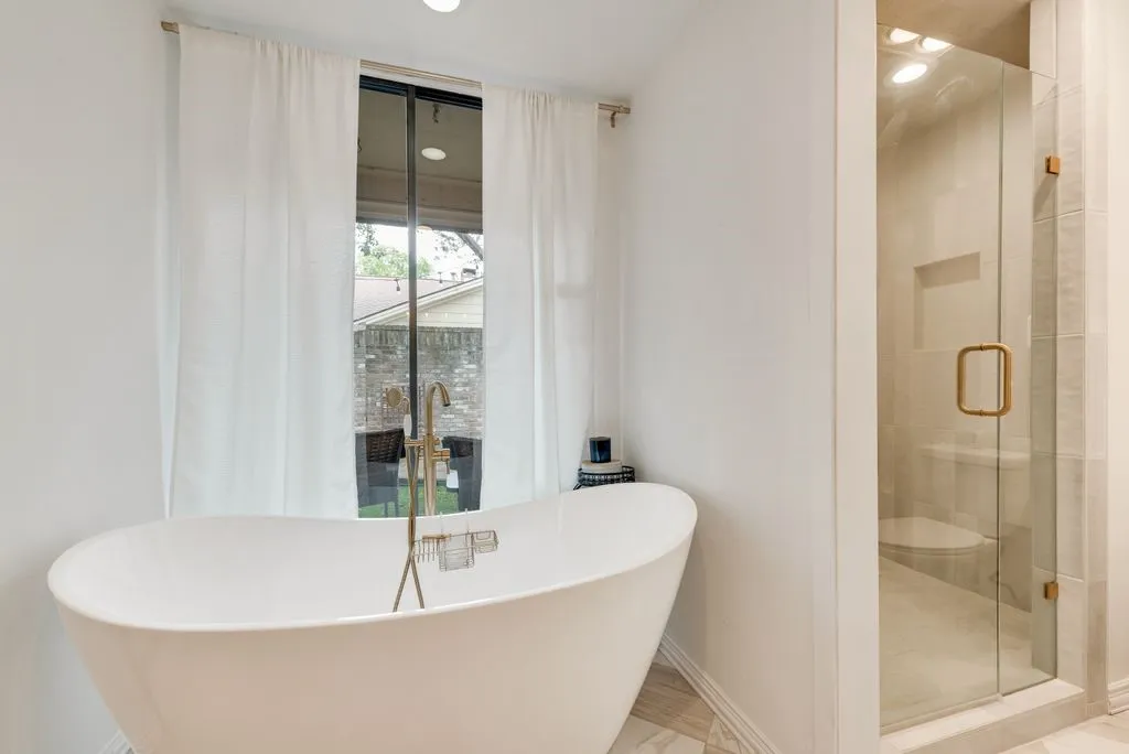 A freestanding soaking tub and glass-enclosed shower create a spa-like feel within the primary bath.