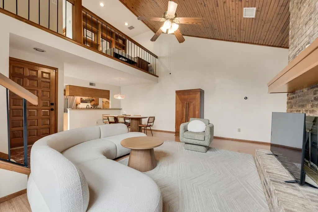 Vaulted ceilings with natural wood detailing add warmth and dimension, complemented by a cozy fireplace below.