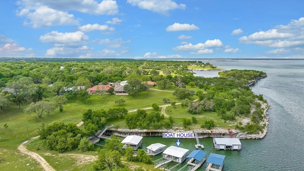 Open to see boathouse location on waterfront, property'swaterfront location, featuring a private boat house with boat slips, and a lush green landscape with mature trees