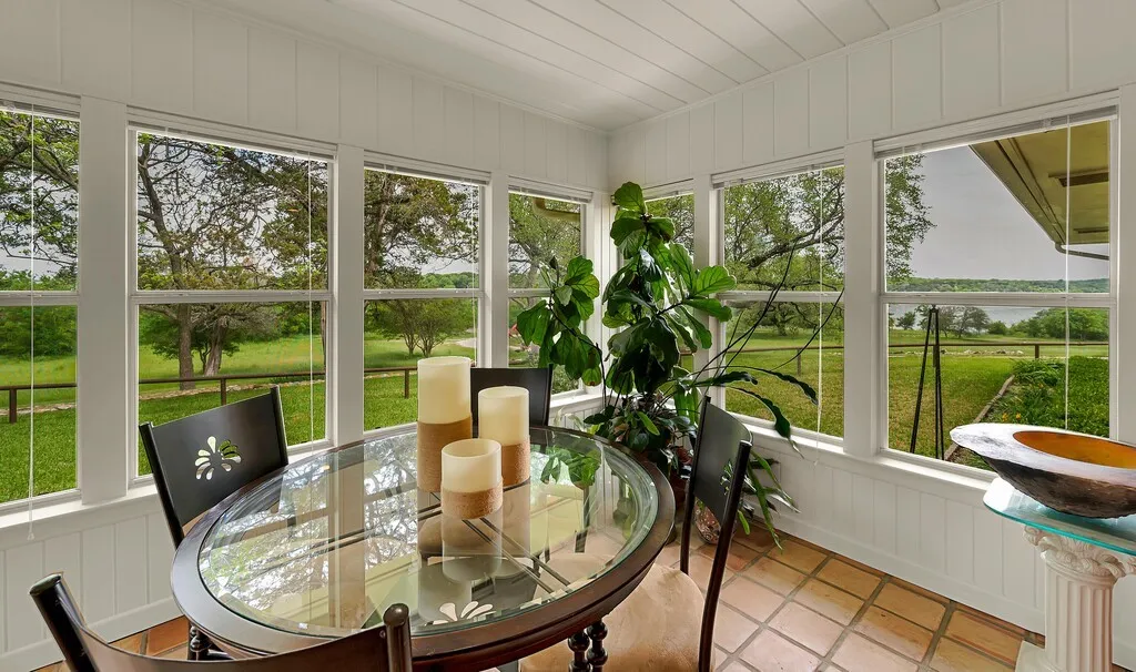 This bright room features extensive windows showcasing views of the outdoors, a tiled floor, and white paneled walls and ceiling