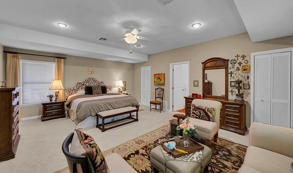 Located in separate  wing. This spacious bedroom features neutral-toned walls, carpeted flooring, and a ceiling fan with integrated lighting